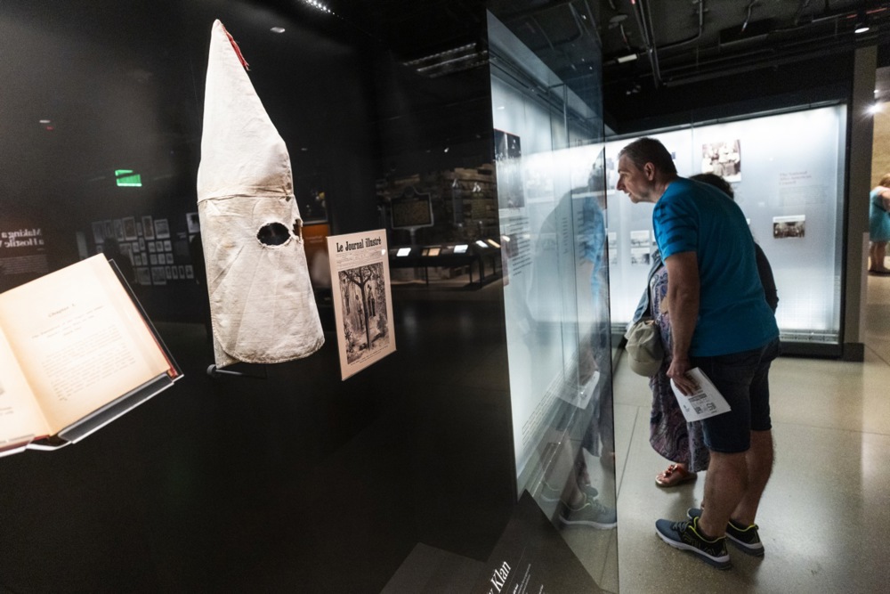 a white kkk mask can be seen in a museum