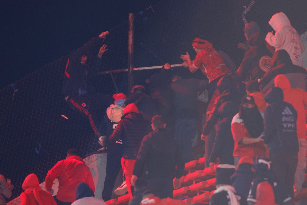 Fans clash in the stands during the CONMEBOL Copa Sudamericana round of 16 soccer match between Independiente and Universidad de Chile, in Avellaneda, Argentina