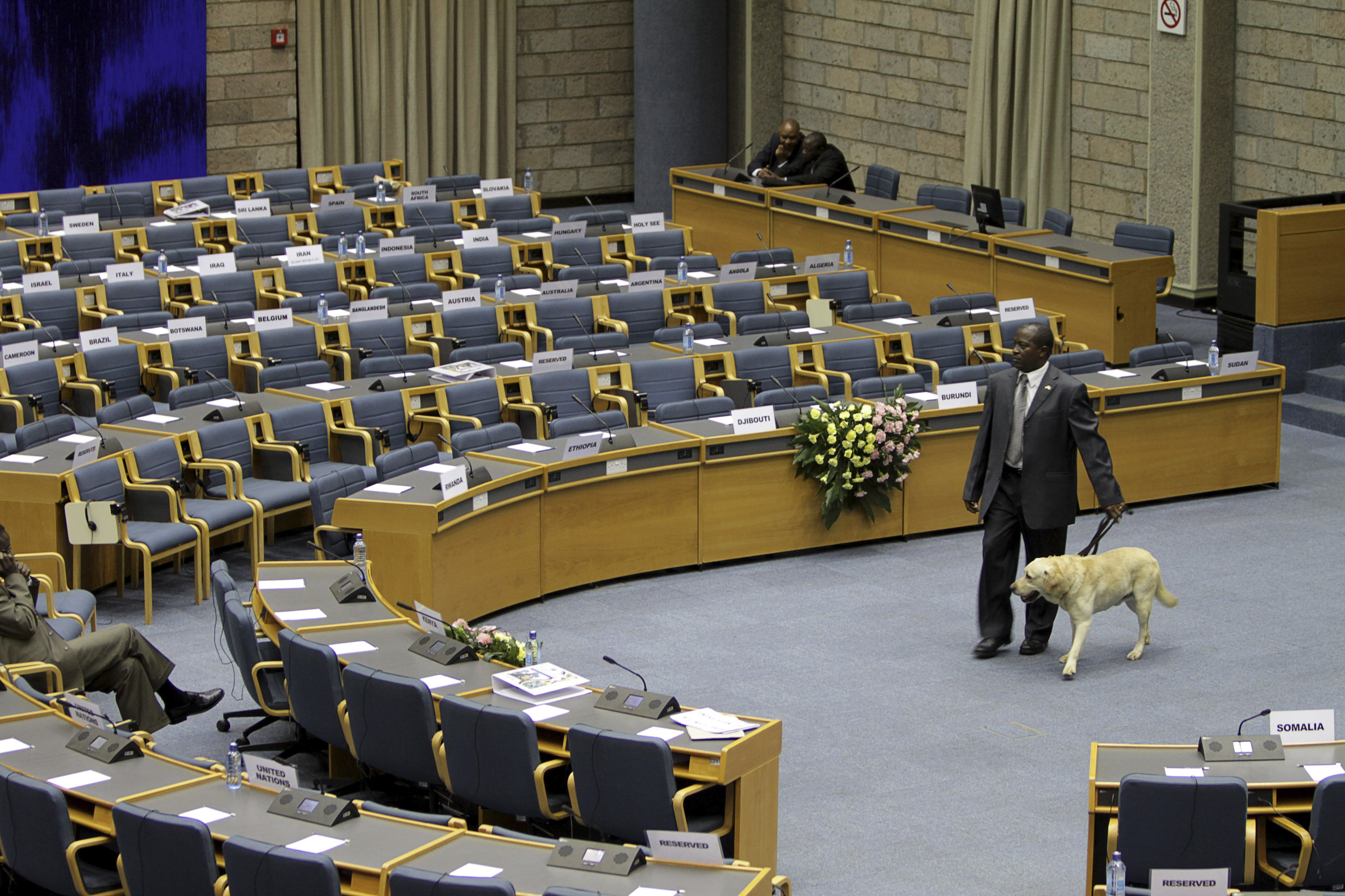 A security officer walks with a sniffer dog through a plenary hall.