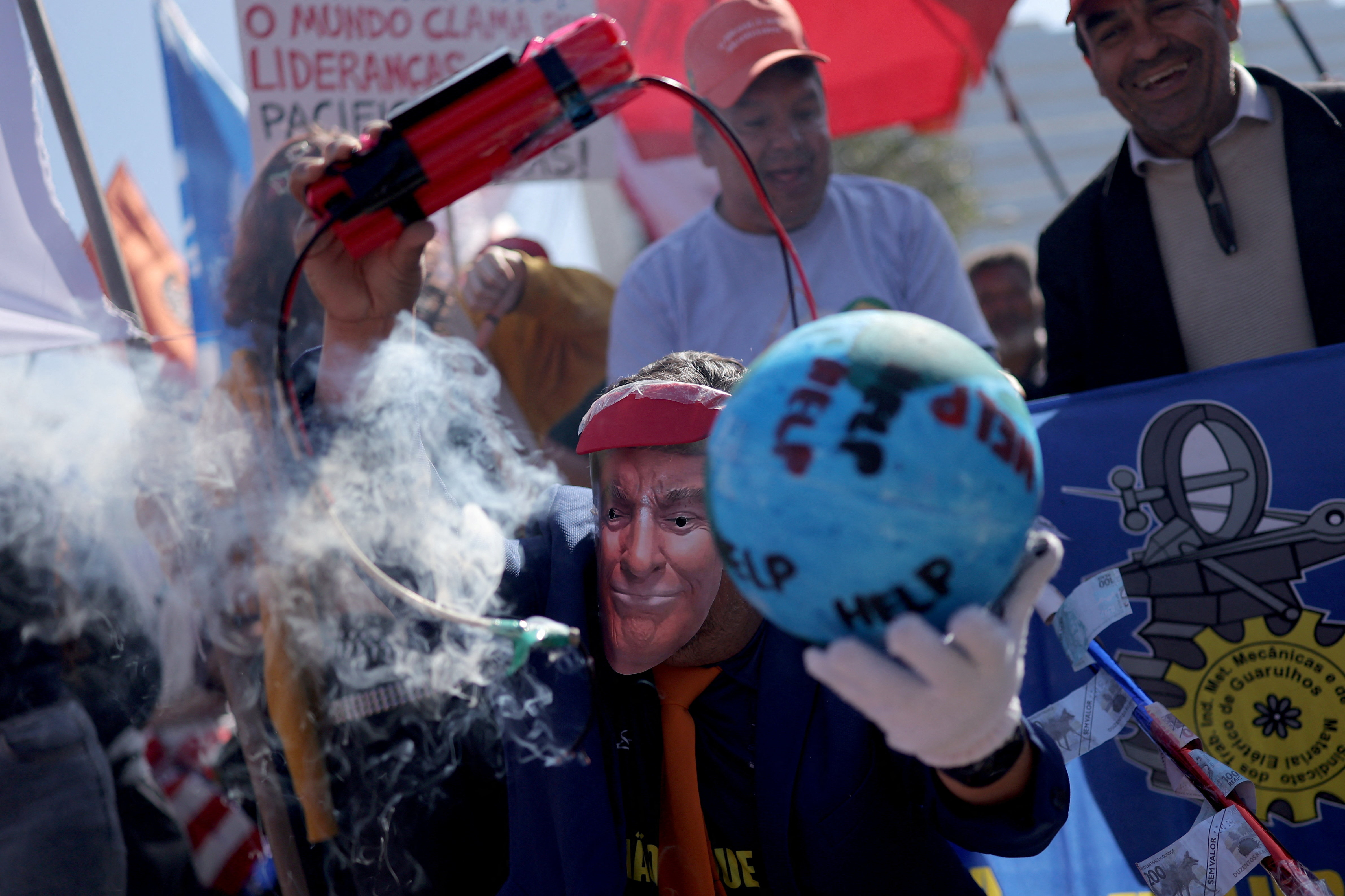 A demonstrator wearing a Trump mask holds up fake dynamite and a model of the globe labelled with the word "help"