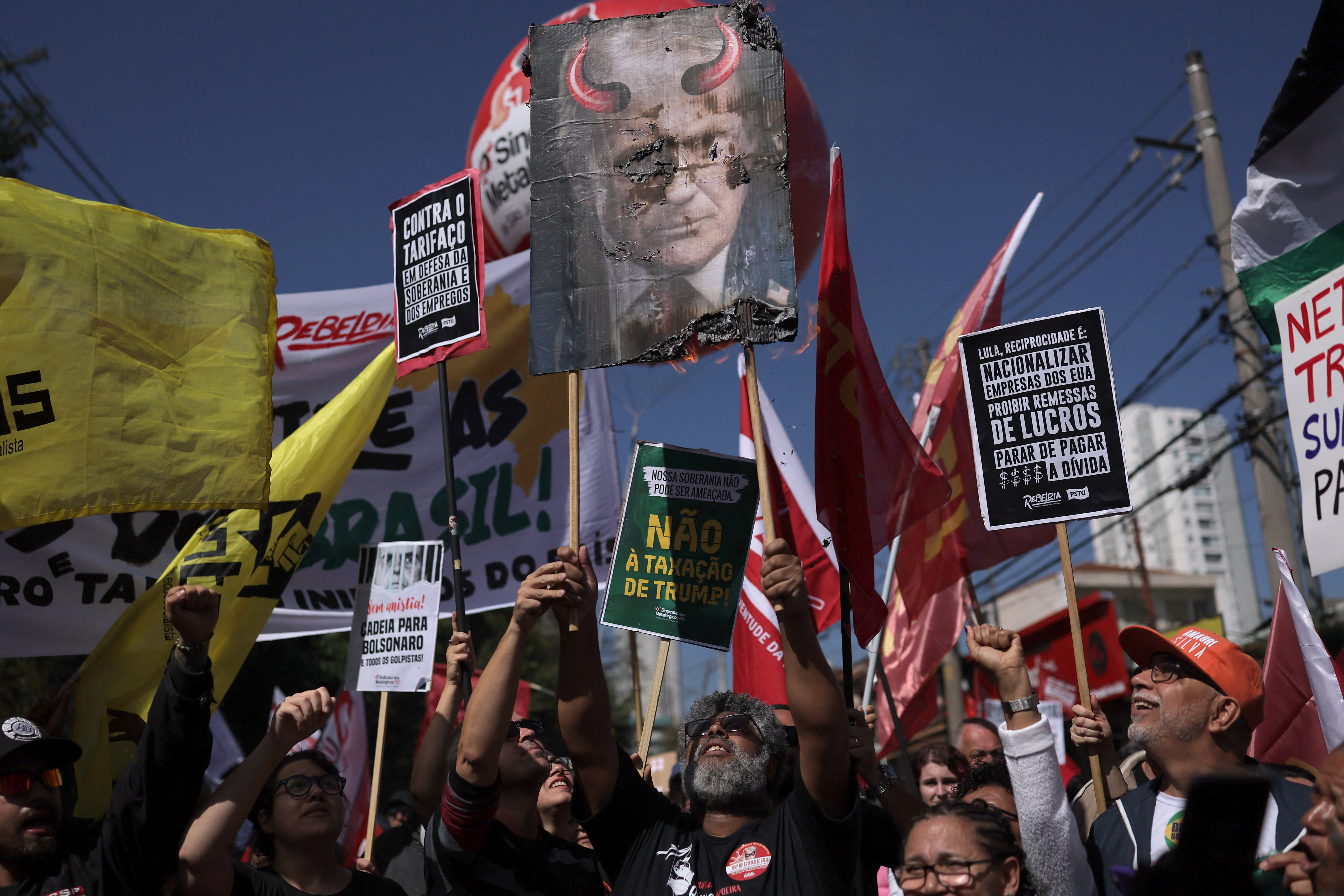 Protesters hold up a placard that shows Trump as the devil.
