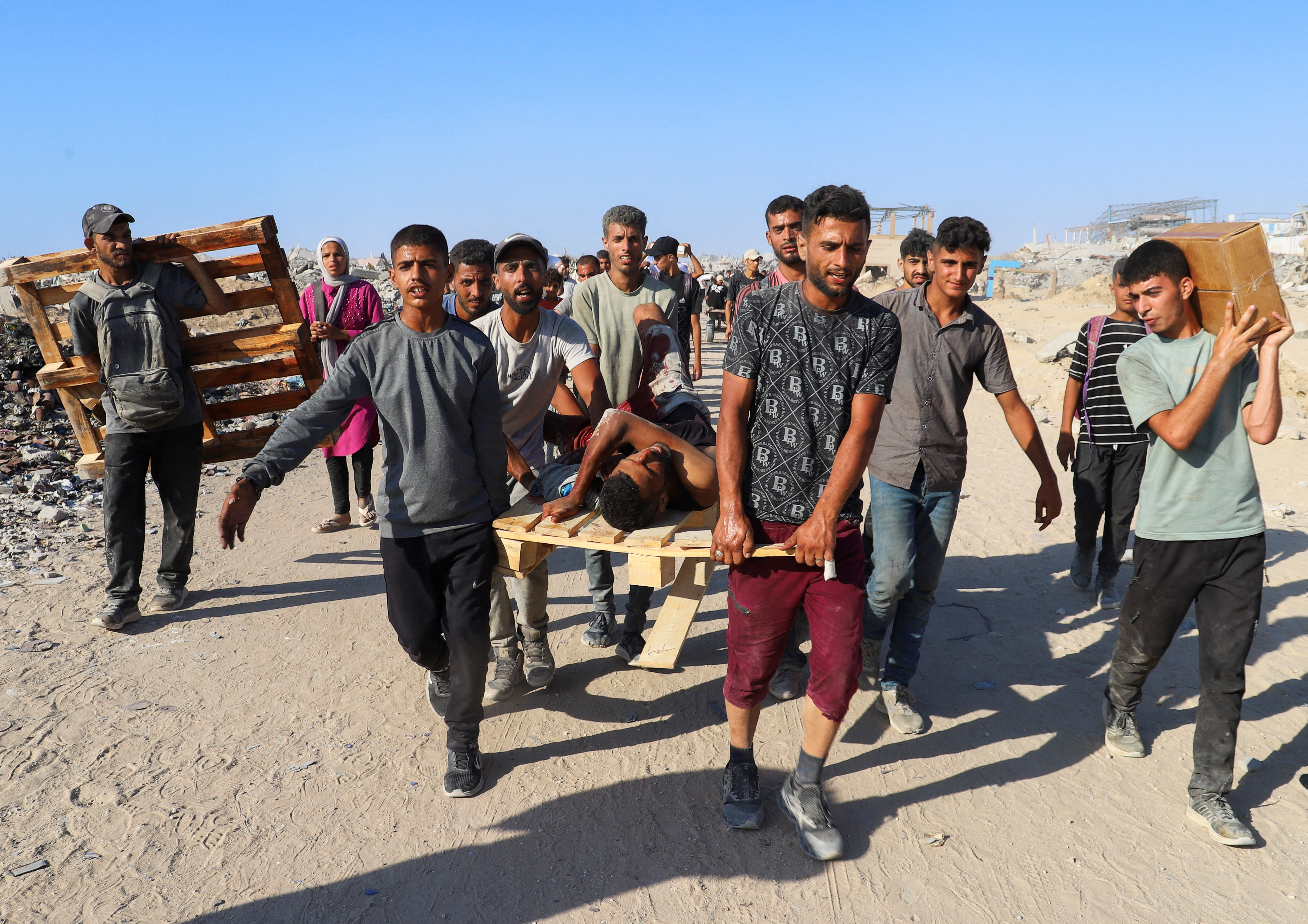 Palestinians carry a person wounded by Israeli fire near an aid point in Beit Lahia, northern Gaza Strip, August 3, 2025. [Ebrahim Hajjaj/Reuters]