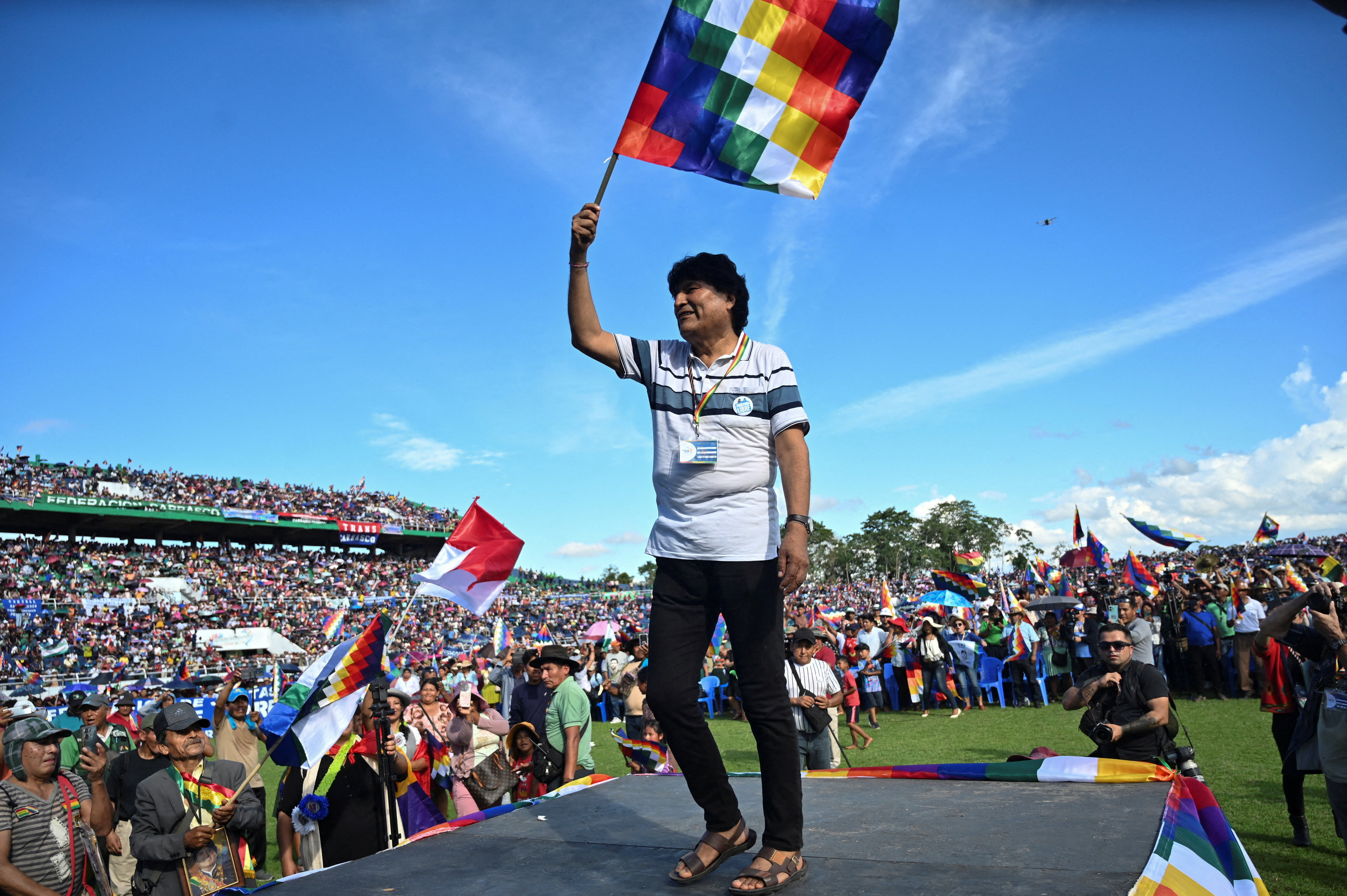 Evo Morales holds up a flag and walks on stage.