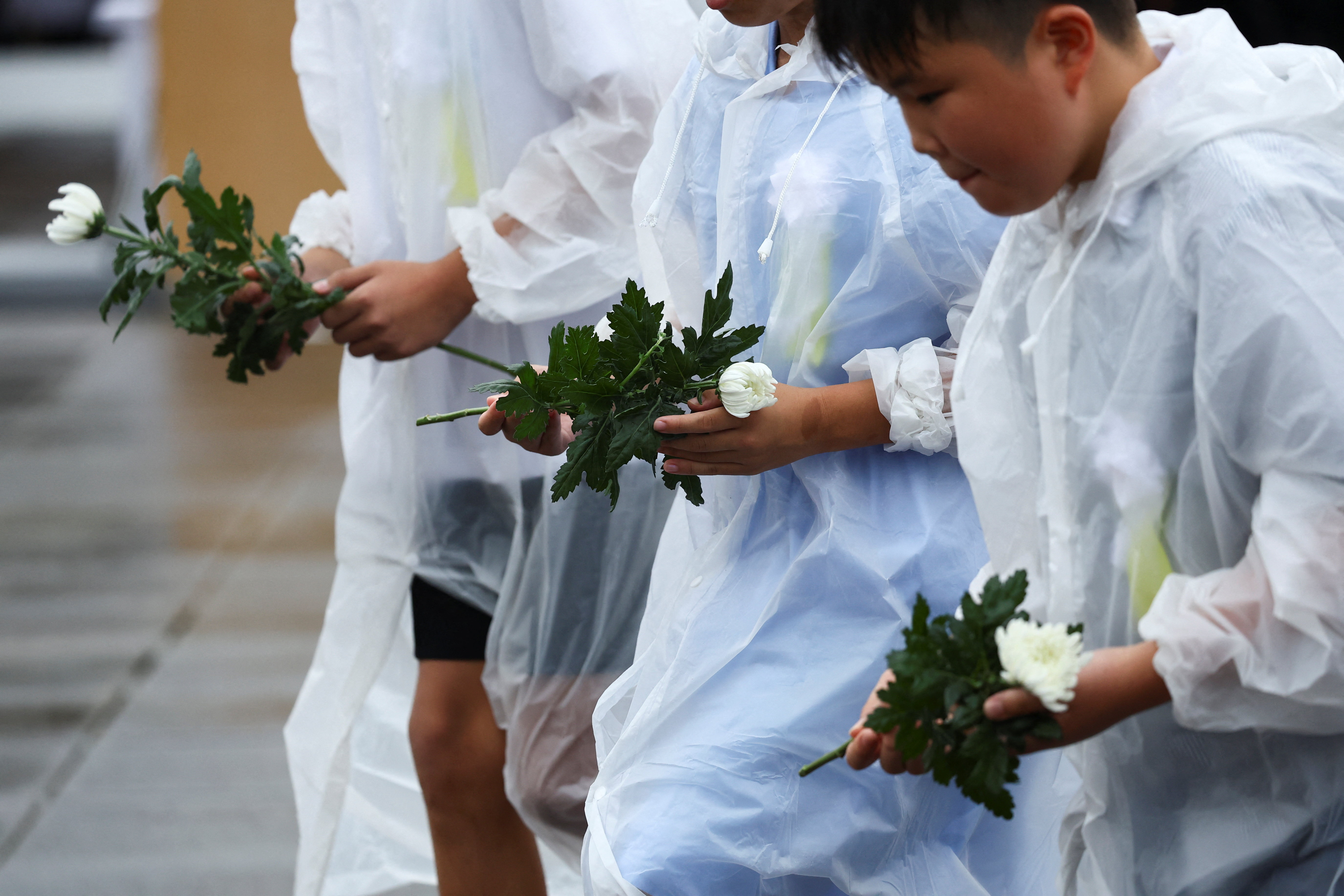 Children hold flowers during a ceremony commemorating the 80th anniversary of the bombing of the city, at Nagasaki's Peace Park in Nagasaki, southwestern Japan, August 9, 2025. REUTERS/Issei Kato