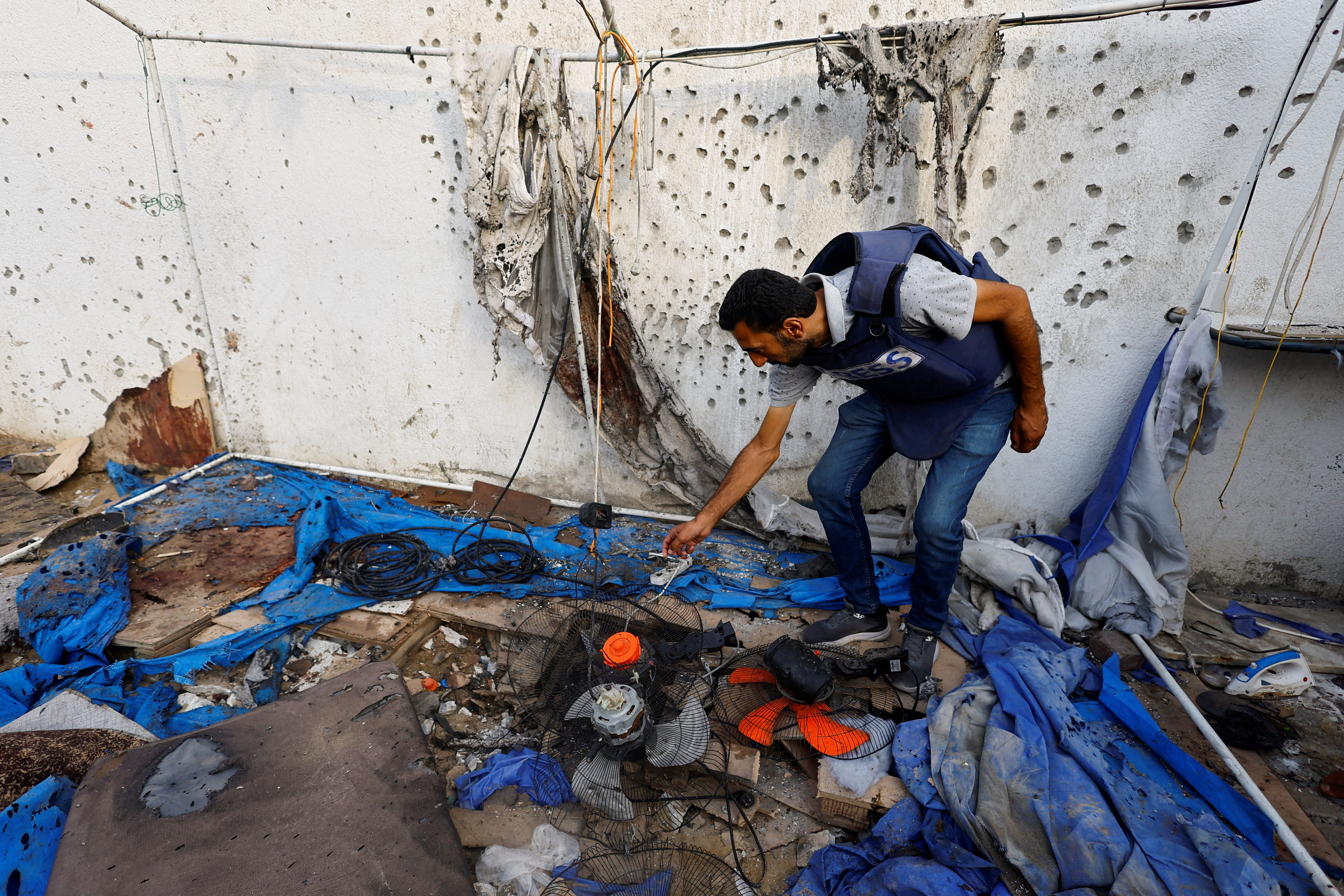 A member of the media inspects the damage at the site of an Israeli strike on a tent that killed journalists.