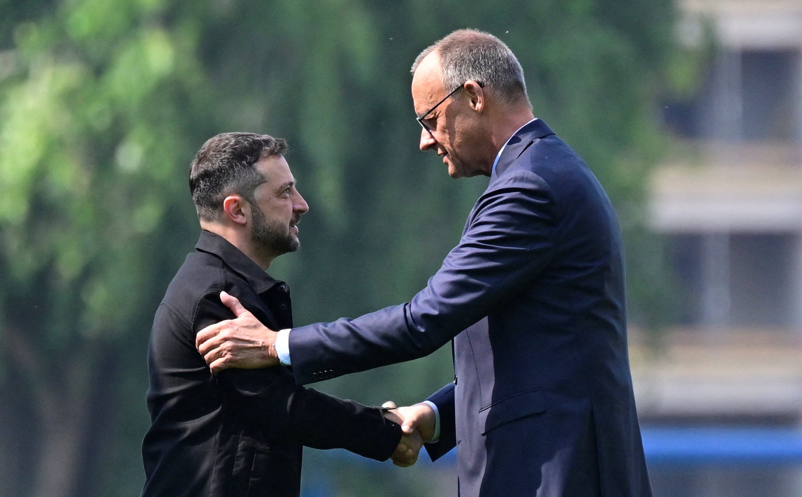 Ukrainian President Volodymyr Zelensky (L) is welcomed by German Chancellor Friedrich Merz upon arrival in the garden of the chancellery in Berlin to join a video conference of European leaders with the US President on the Ukraine war ahead of the summit between the US and Russian leaders, on August 13, 2025. European leaders will hold online talks with US President Donald Trump, hoping to convince him to respect Ukraine's interests when he discusses the war with Putin in Alaska on Friday. JOHN MACDOUGALL/Pool via REUTERS