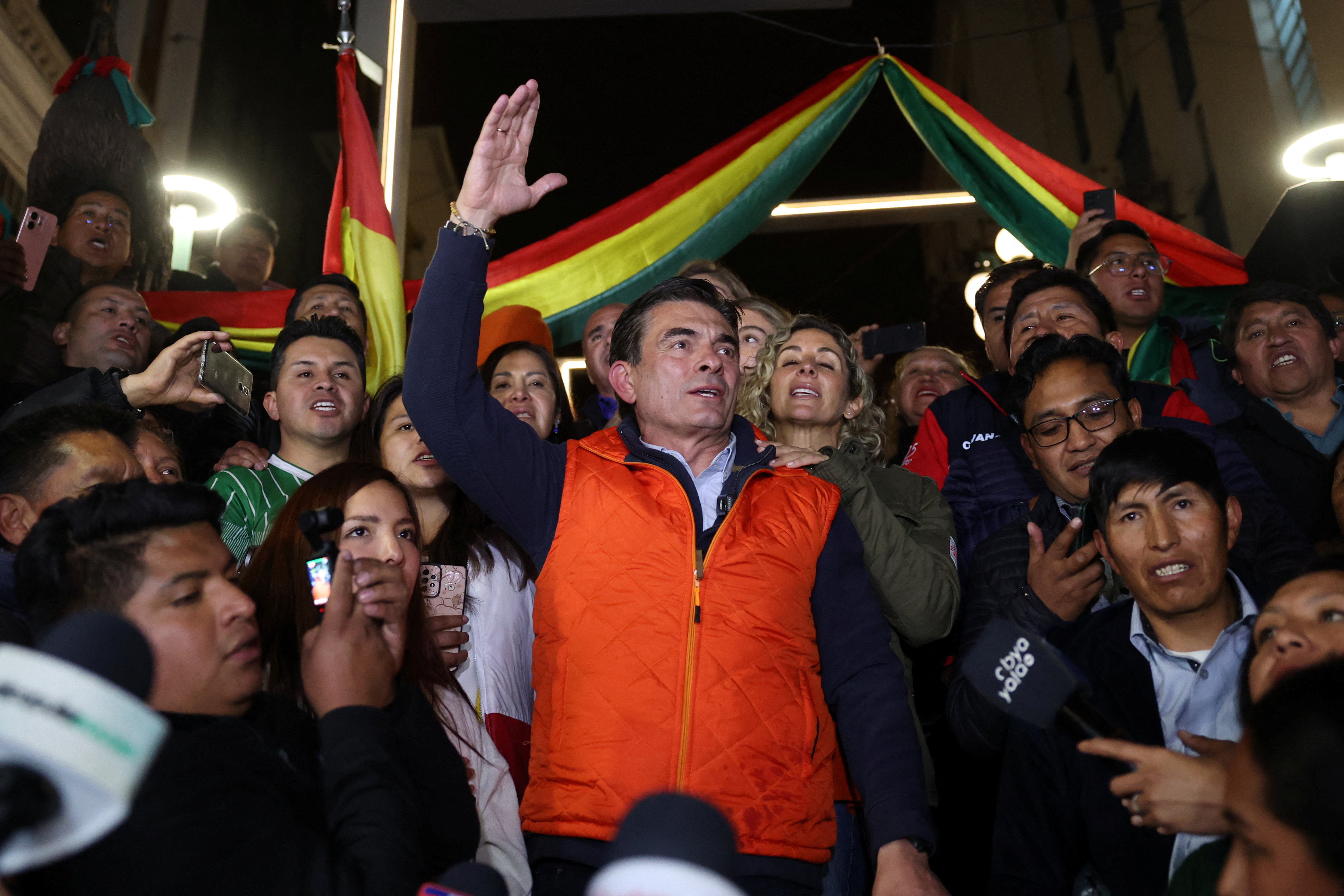 a man in a orange vest celebrates