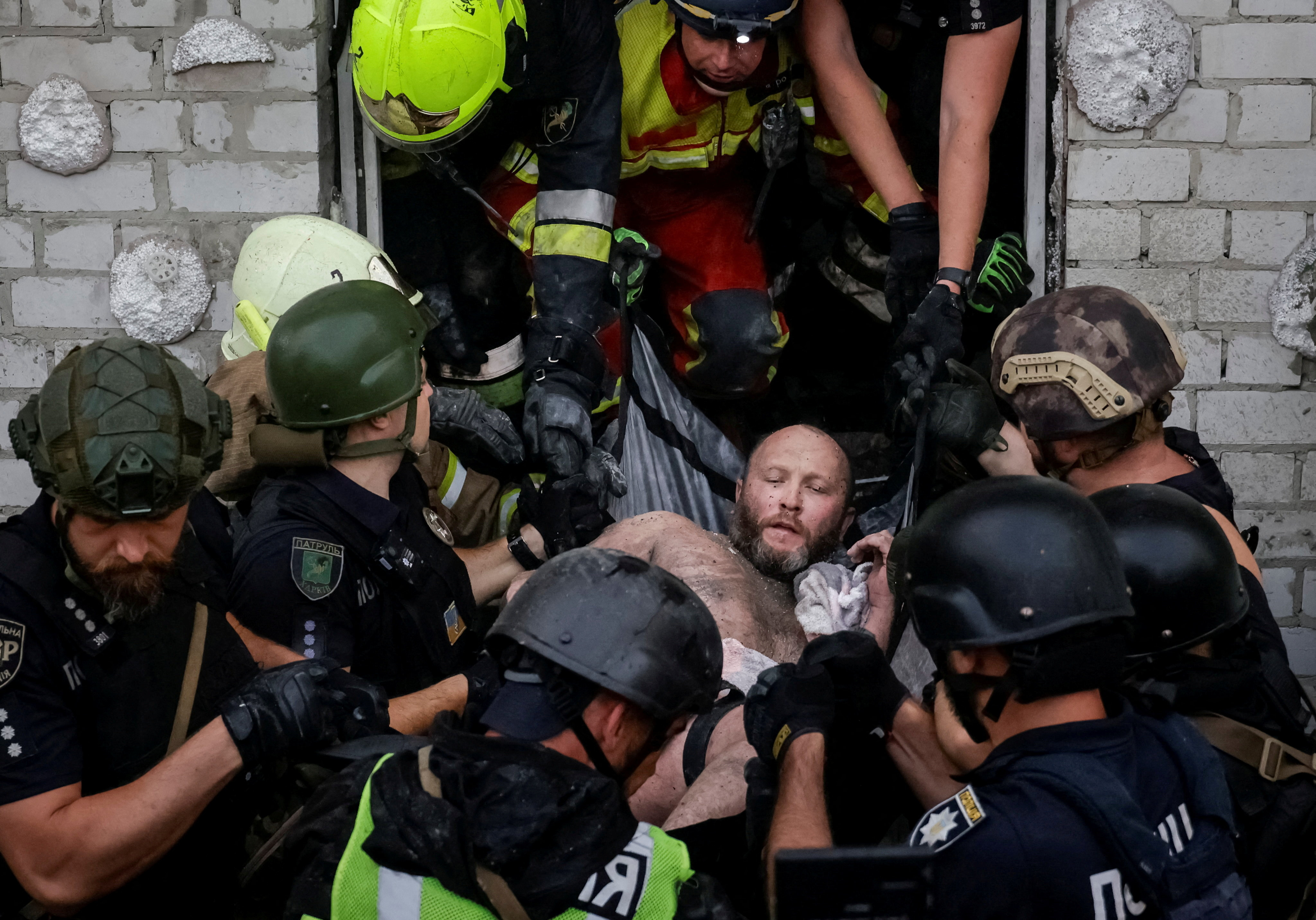 Rescuers and police officers carry a man rescued from debris at the site of an attack.