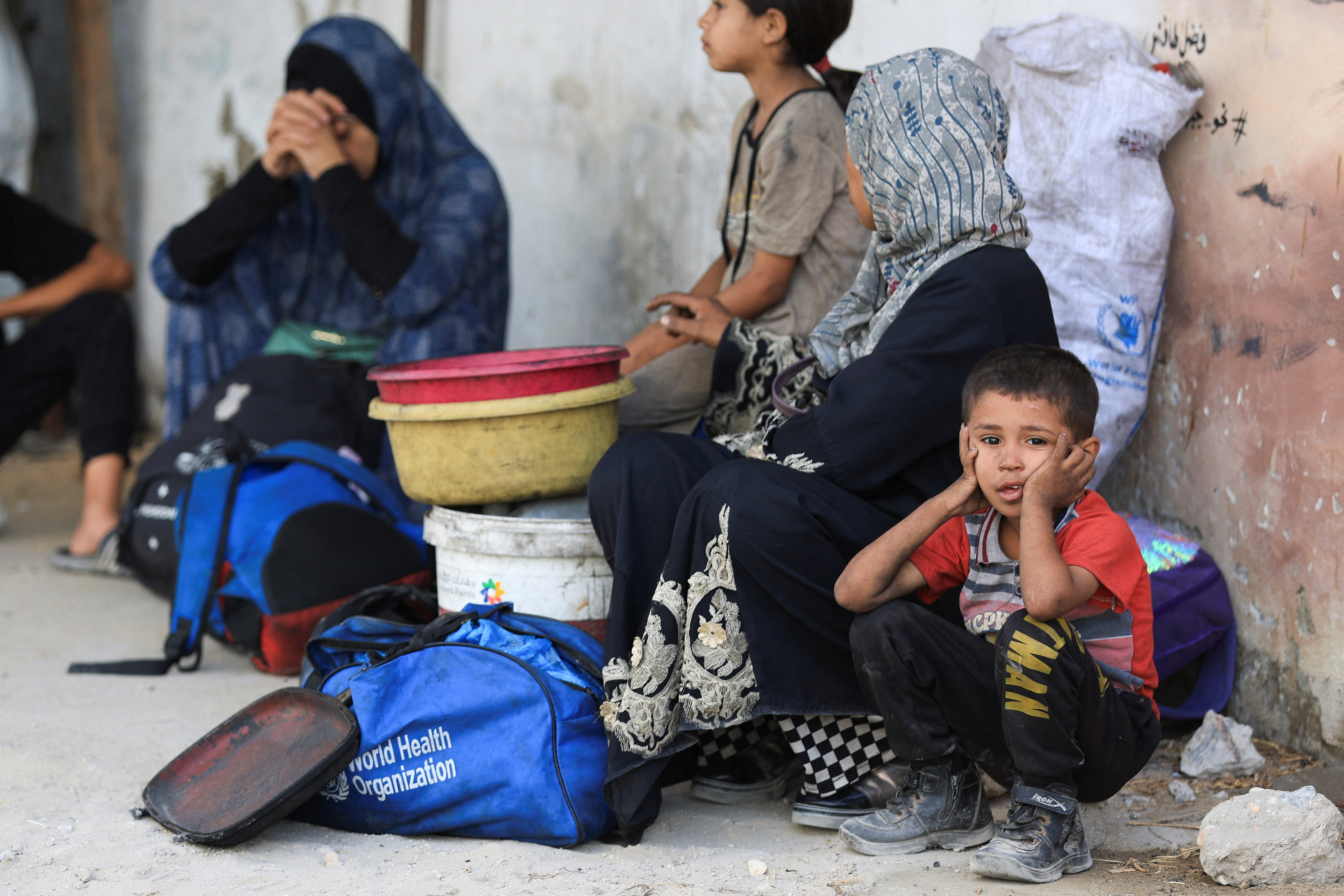 A child looks on as Palestinians sit on their belongings in Gaza
