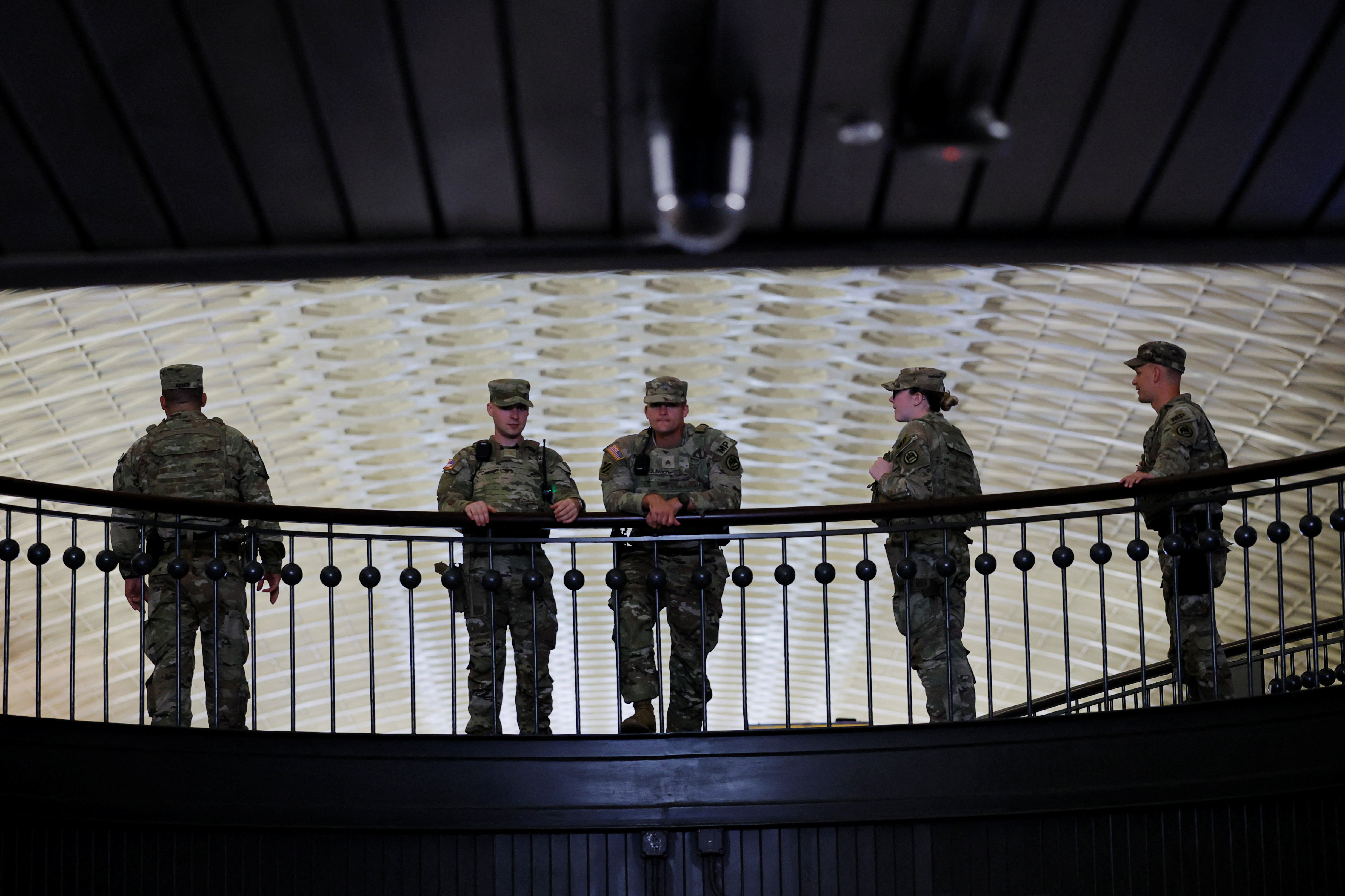 National Guard troops lean over a balcony ledge.