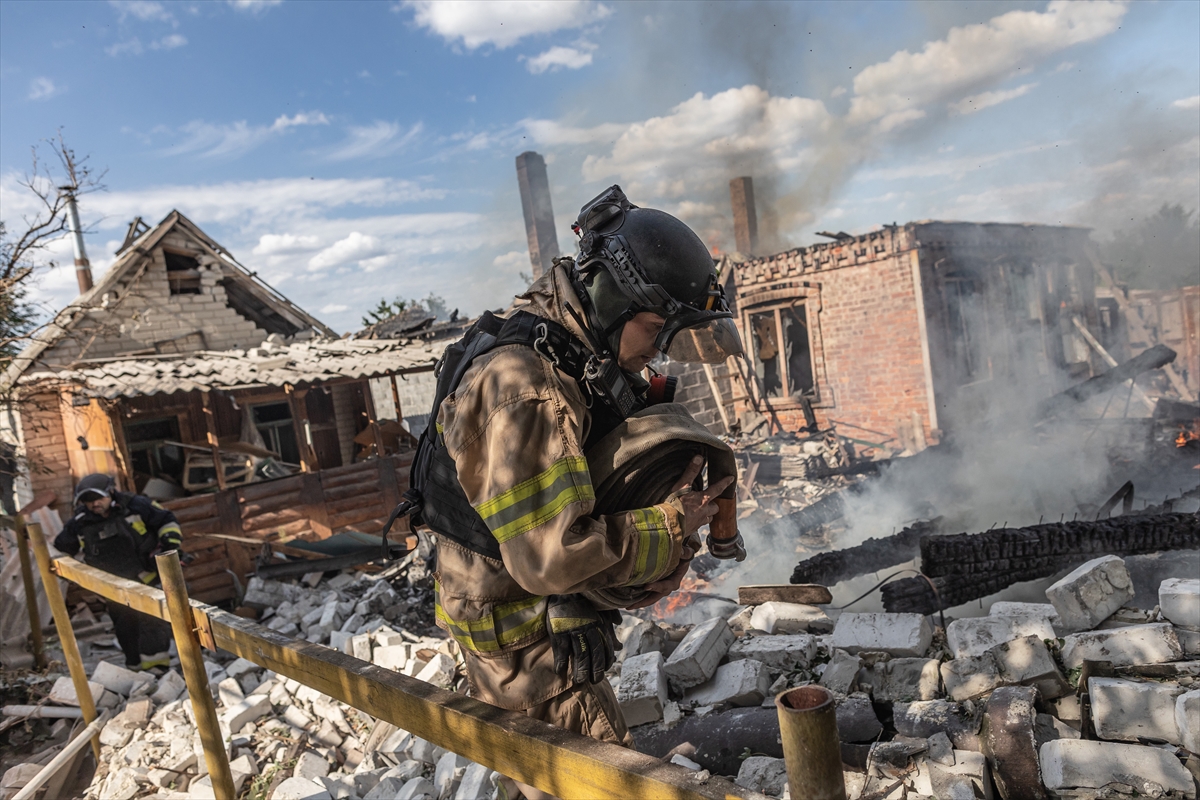 a firefighter walks in front of a smouldering house fire