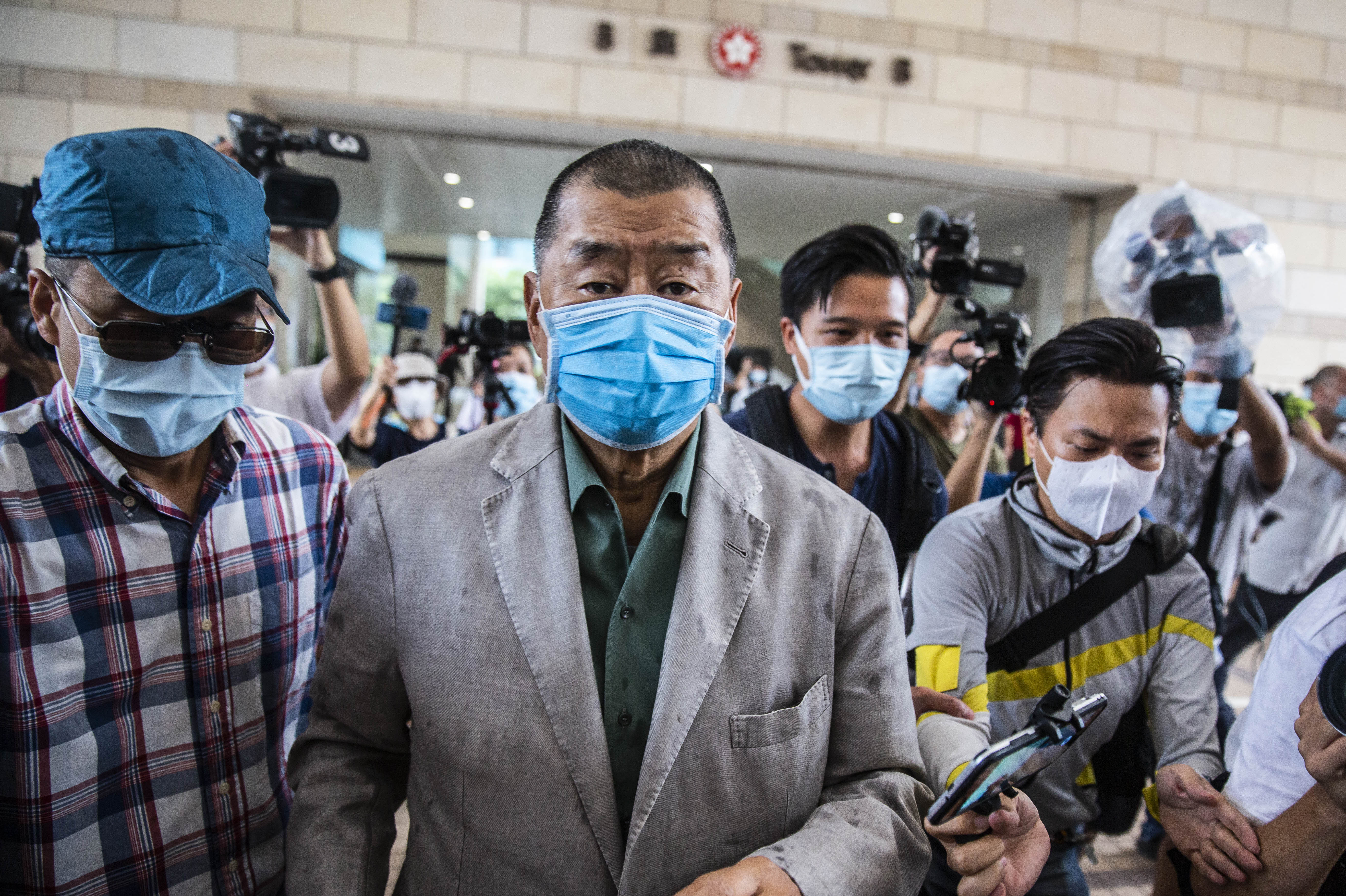 Jimmy Lai pushes through a media pack as he arrives at court.