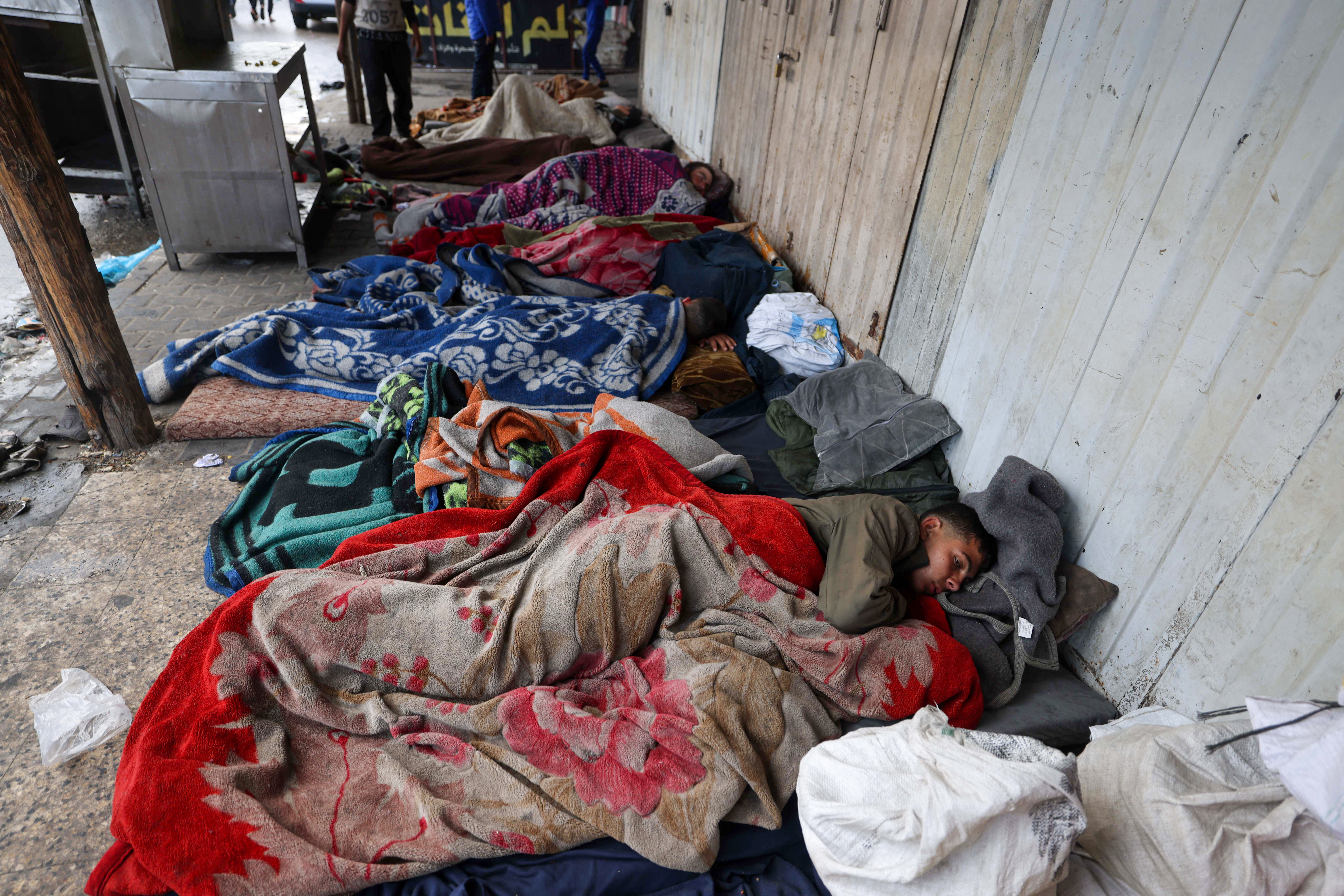 Displaced Palestinians sleep beside a street in Rafah, southern Gaza Strip, on April 10, 2024, amid the ongoing conflict between Israel and the militant group Hamas. (Photo by MOHAMMED ABED / AFP)