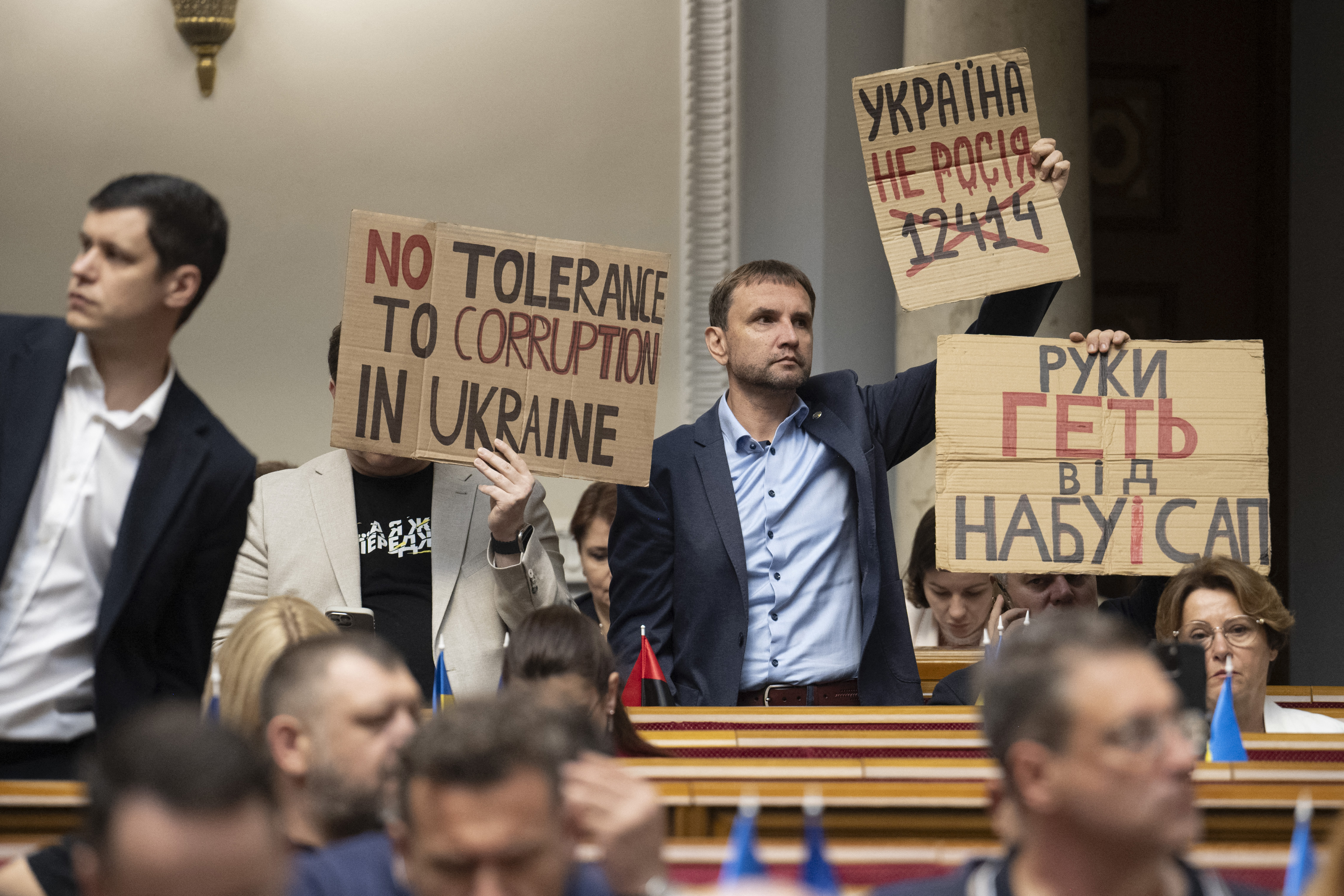Ukrainian lawmakers protest with placards as they vote on a bill to replace a law that curbed the powers of anti-graft bodies