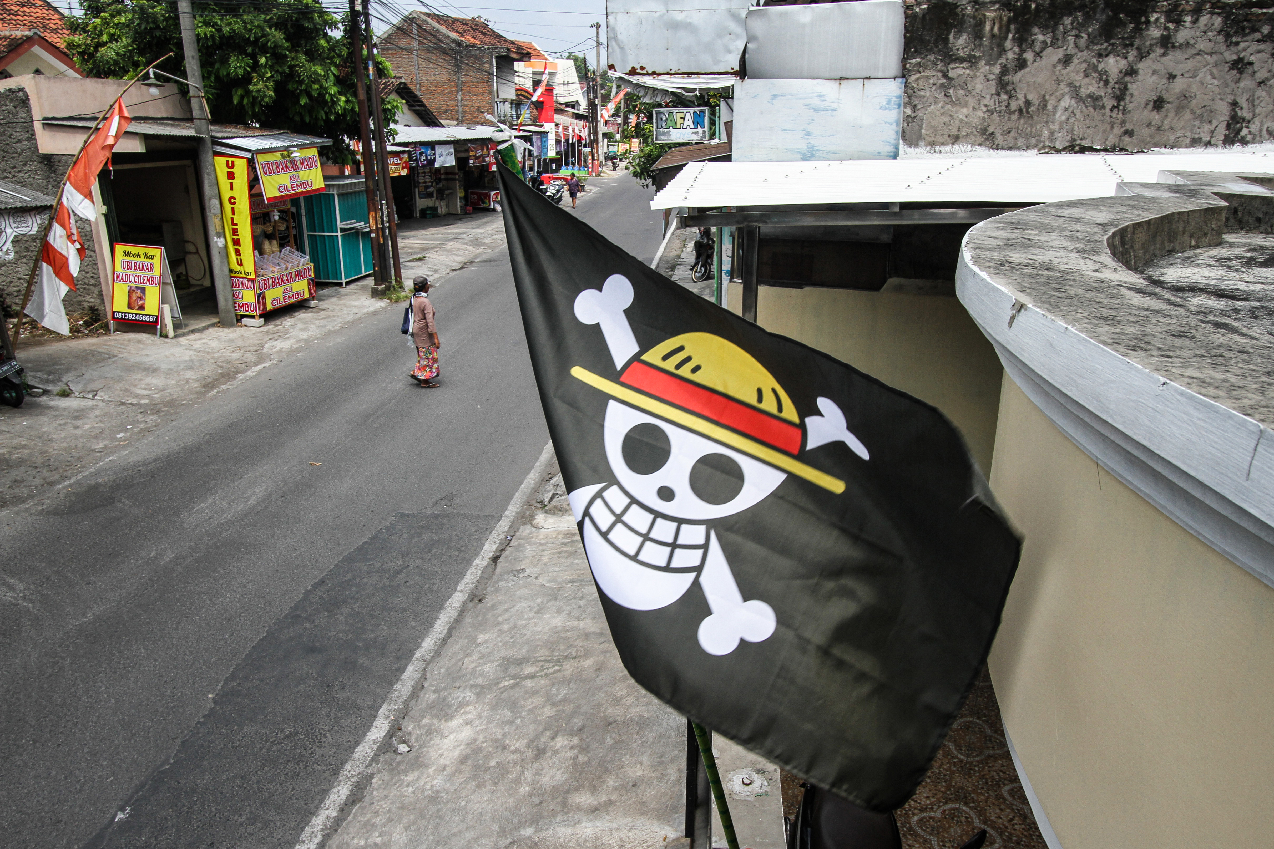 A pirate flag from the Japanese anime One Piece, installed a week earlier to follow an internet trend using the symbol to criticise government policies, is seen at a house in Solo, Central Java, on August 7, 2025, ahead of the countrys 80th Independence Day. As Indonesia's independence day approaches red and white flags will be flown across the country, but a viral anime pirate banner has drawn government threats against flying the swashbuckling ensign. A Jolly Roger skull and bone symbol topped with a straw hat from Japan's anime series 'One Piece' has caused concern among officials in Jakarta that it is being used to criticise President Prabowo Subianto's policies. (Photo by DIKA / AFP) / TO GO WITH 'INDONESIA-POLITICS-PROTEST-ANIME, FOCUS' BY DESSY SAGITA &amp; JACK MOORE