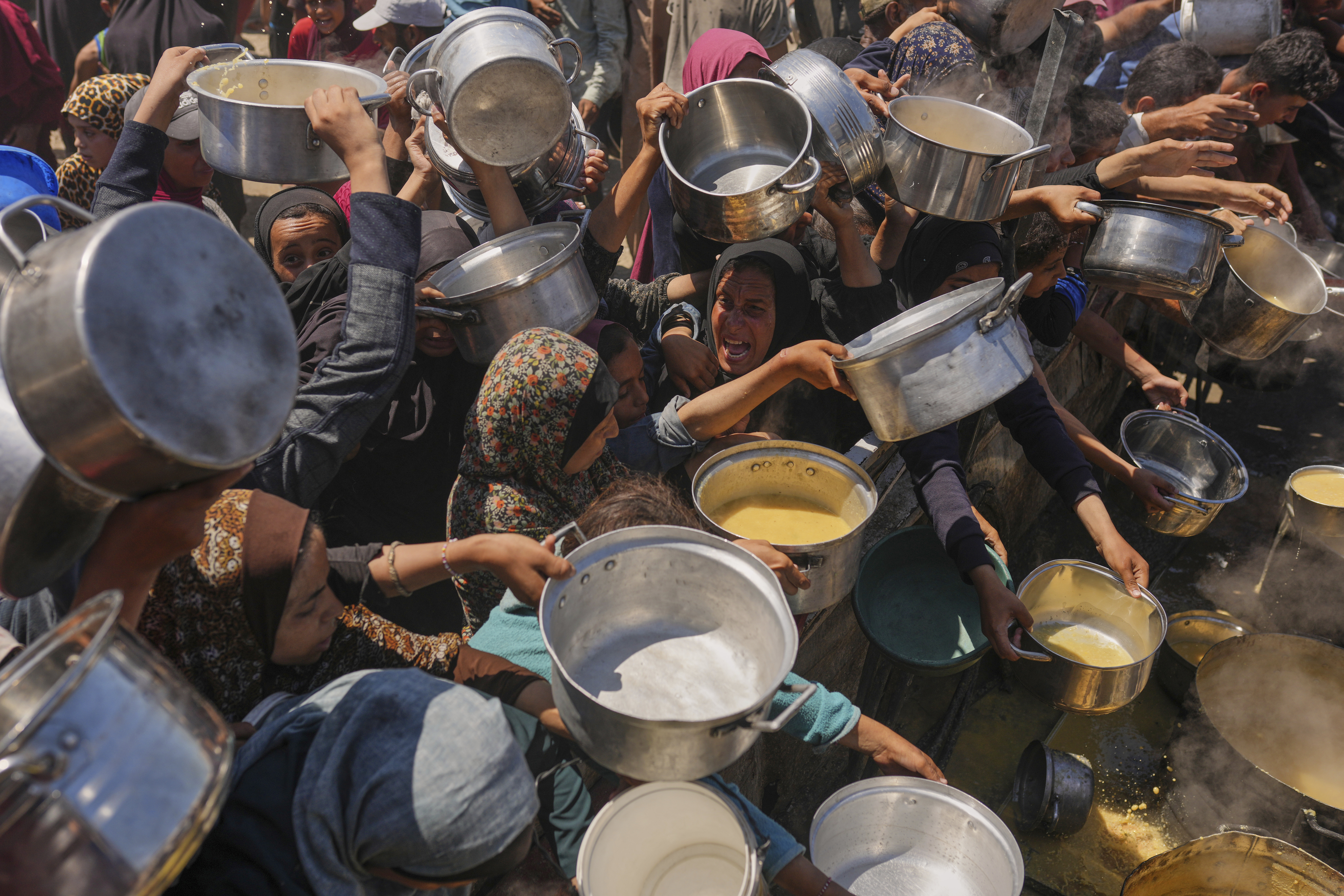 Palestinians struggle to get donated food at a community kitchen in Gaza City, northern Gaza Strip,