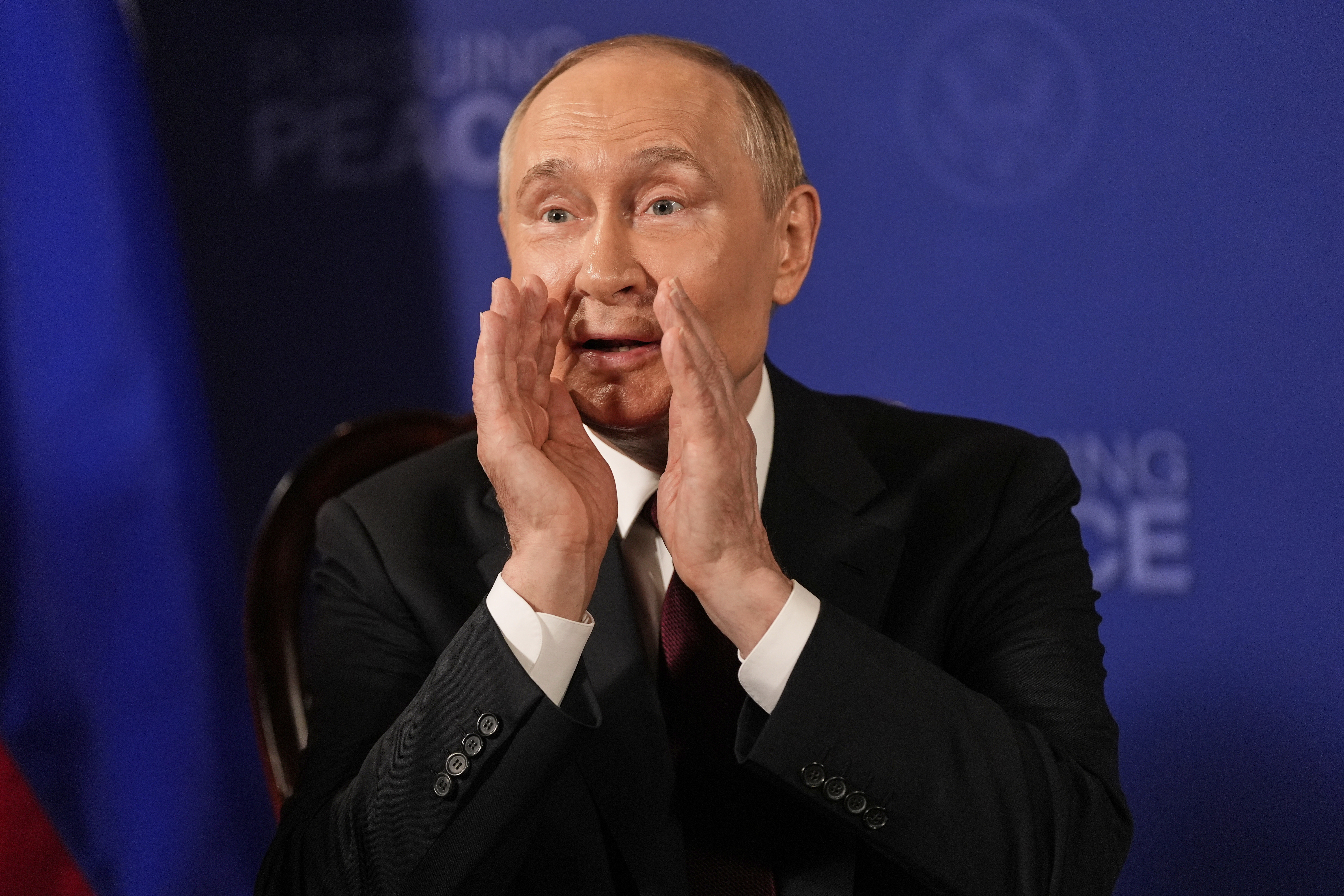 Putin cups his hands around his mouth to speak at a media appearance.