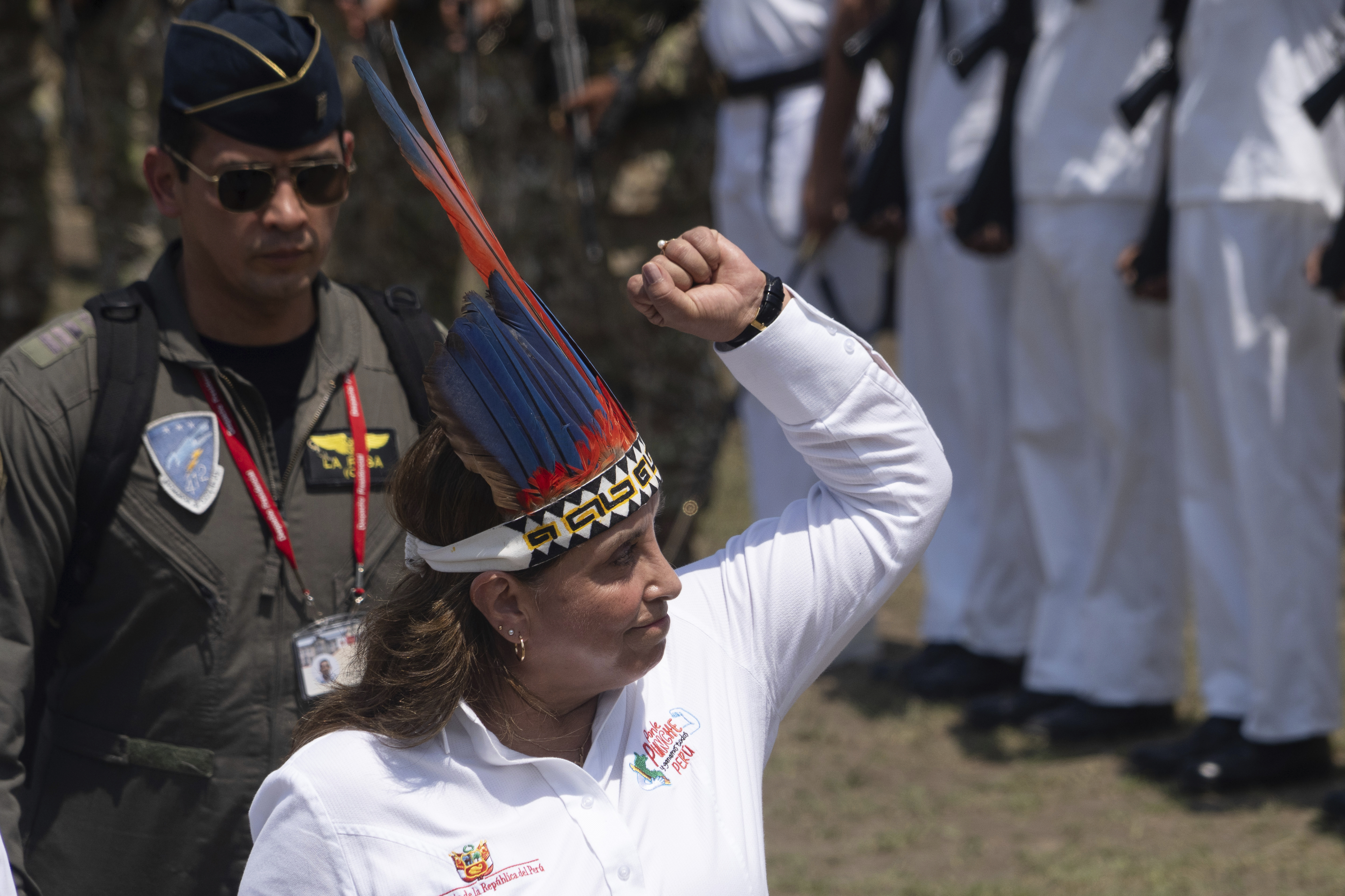 Dina Boluarte raises a fist while wearing an Indigenous headdress.