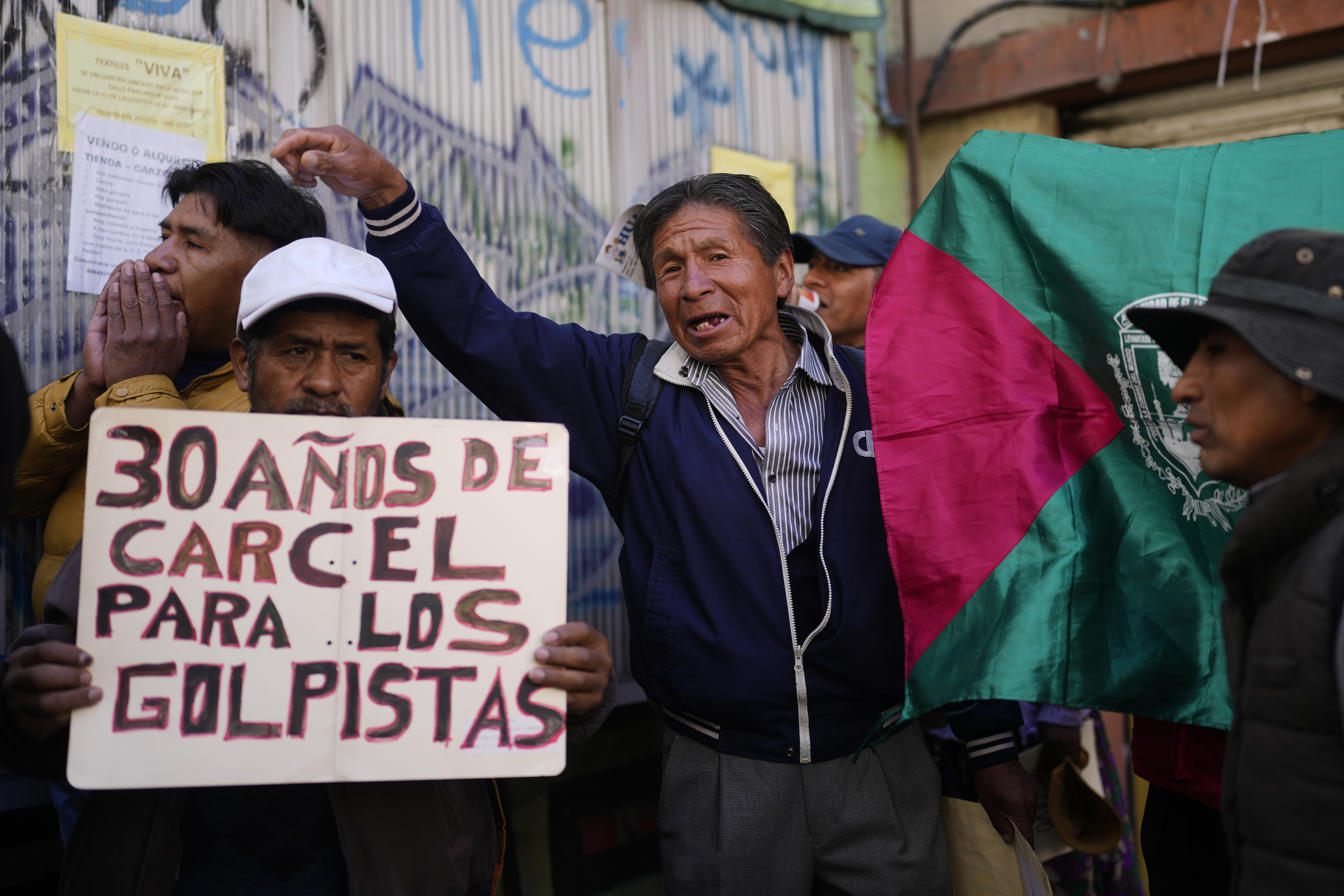 A protester holds up a sign that reads in Spanish, "30 years in prison for the coup plotters"