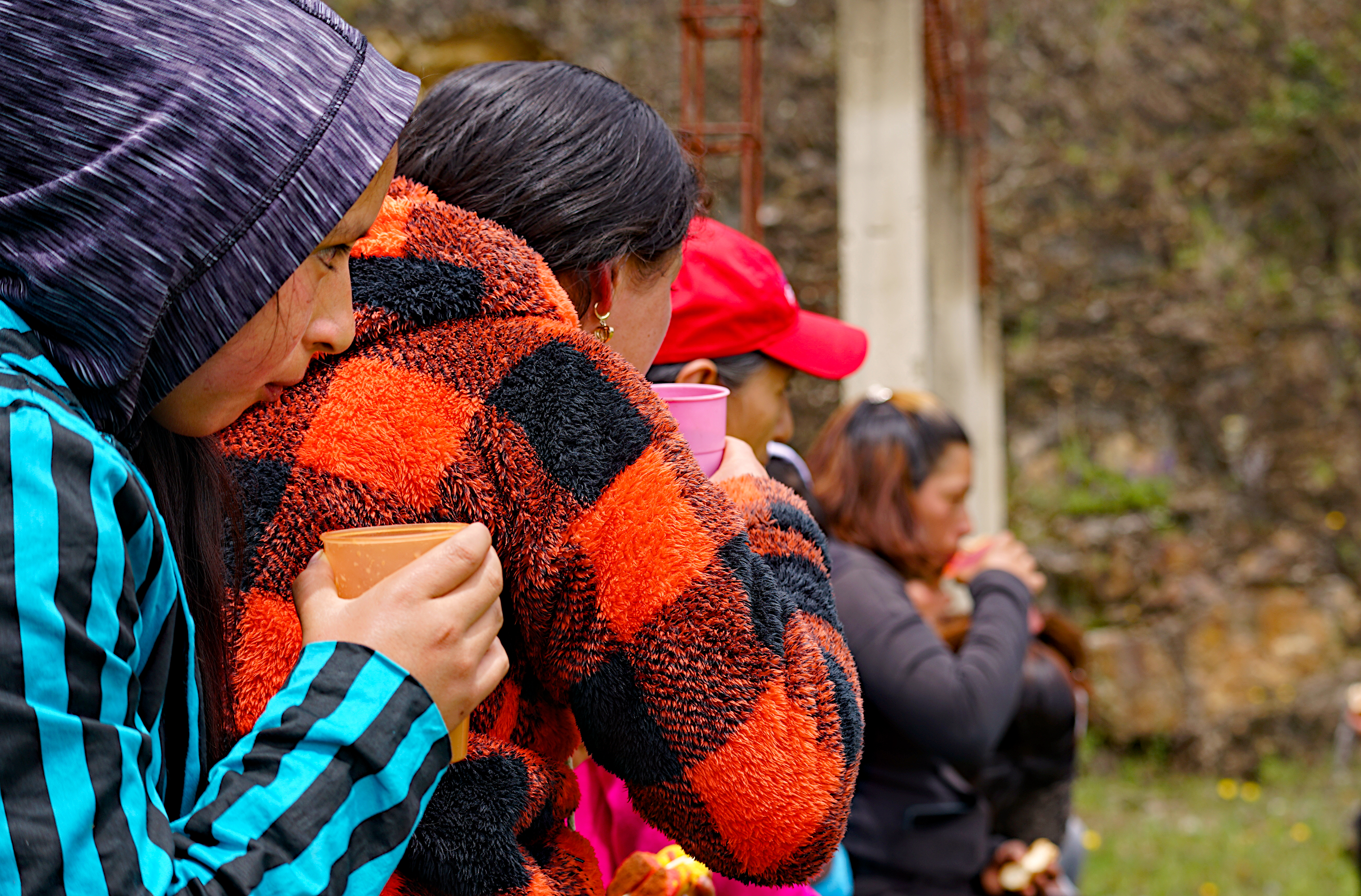 A row of Rio Blanco residents drink hot drinks on a damp day outdoors