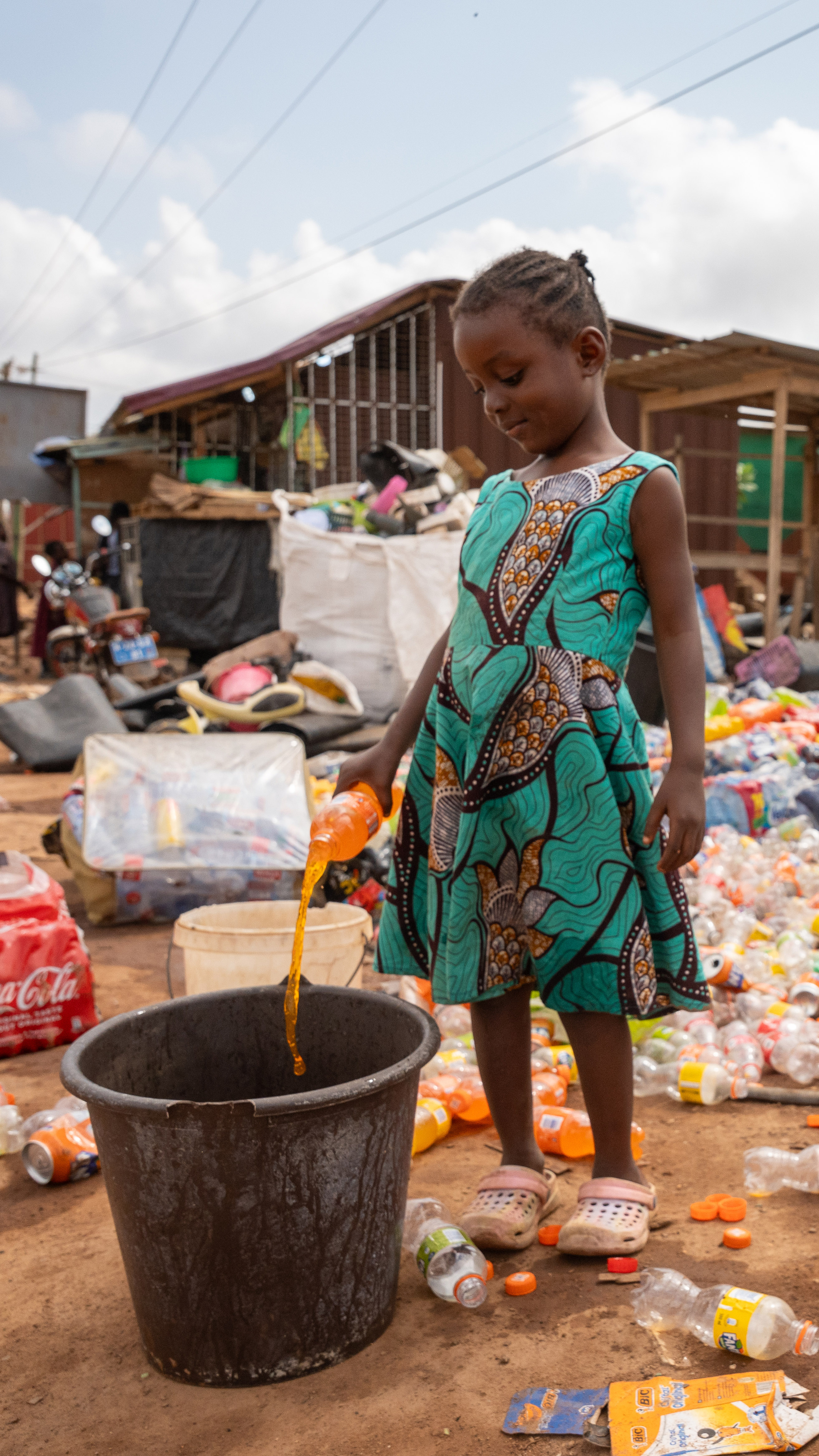 Children help sort plastic outside Lydia Bamfo's waste collection yard [Costanza Gambarini/SourceMaterial]