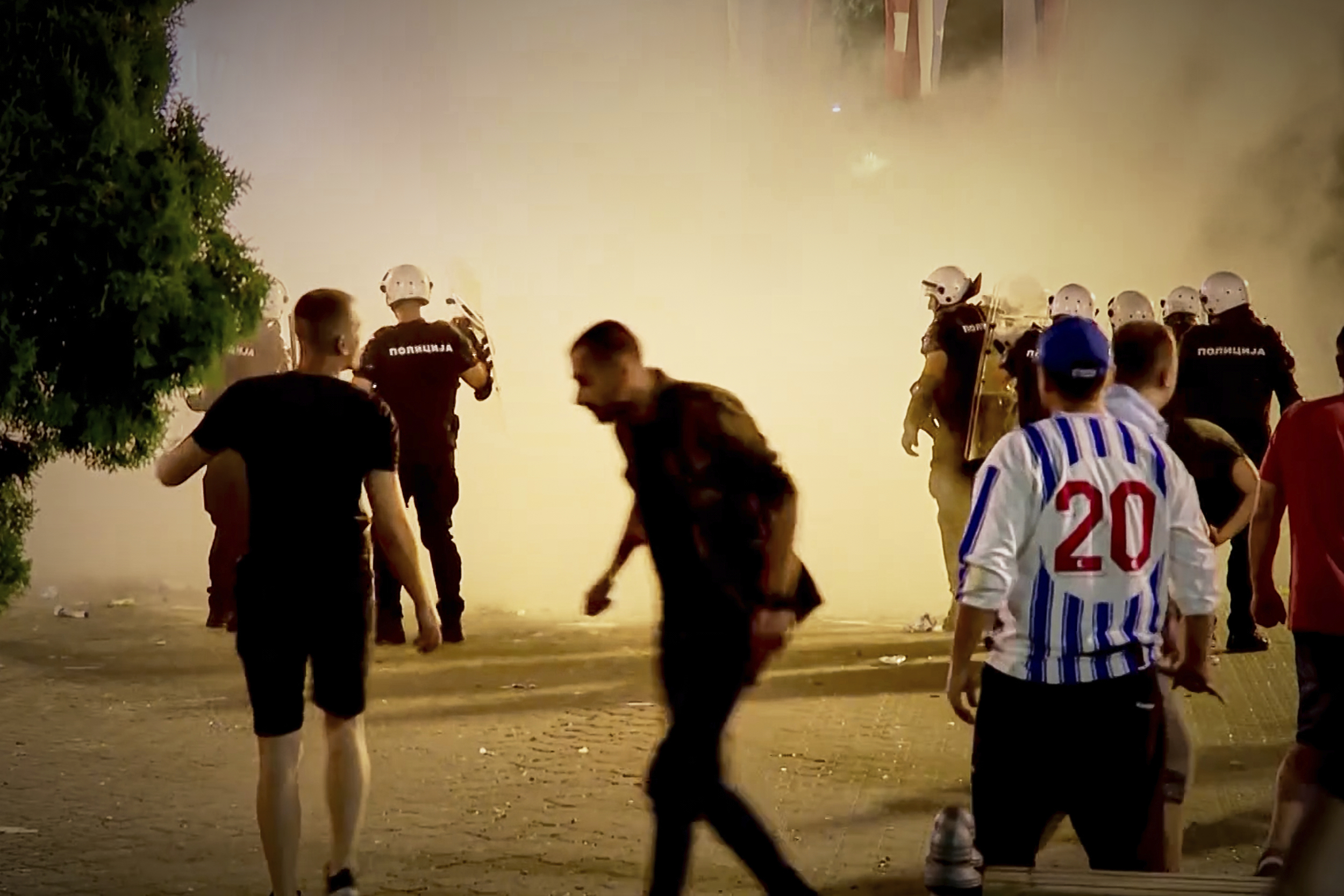 An image taken from video shows protesters and riot police engulfed by smoke as clashes erupted at protests in Vrbas, Serbia, Tuesday, Aug. 12, between opponents and supporters of the government in an escalation of tensions following more than nine months of persistent demonstrations against populist President Aleksandar Vucic. (N1 Serbia via AP)