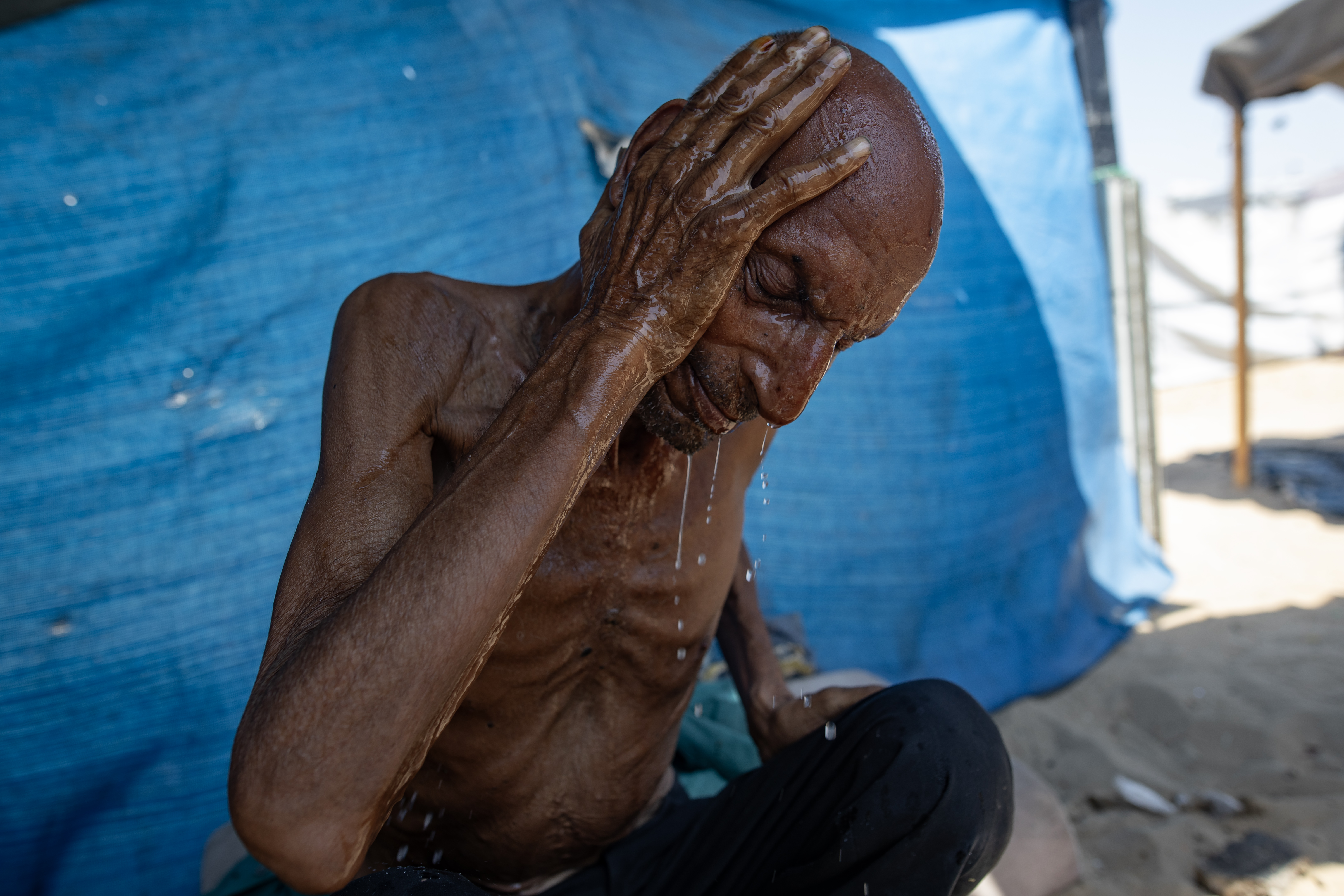 epa12281894 Internally displaced elderly Palestinian man Salim Asfour, washes his face outside his family’s tent in Khan Younis, southern Gaza Strip, 03 August 2025. Salim, 85, suffers from severe malnutrition, which in recent months has led to the loss of over 40 kilograms of his body weight. When food is available, Salim gives most of his rations to his family, and his advanced age makes him more vulnerable to the effects of malnutrition. More than 170 Palestinians, the majority of whom children, have died of malnutrition in Gaza since Israel blocked all supplies from entering the Strip in March 2025, the Palestinian Ministry of Health said on 03 August. EPA/HAITHAM IMAD