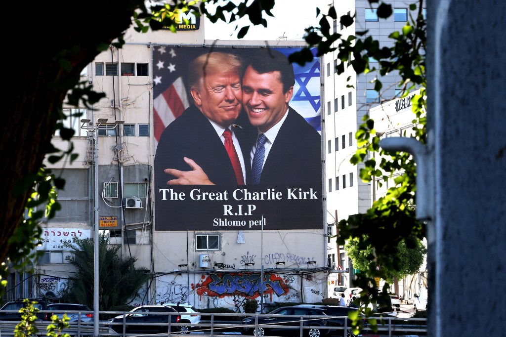 A billboard showing an image of US President Donald Trump (L) embracing US prominent right-wing activist Charlie Kirk, who was hit by a single bullet while addressing a large crowd at Utah Valley University in the town of Orem on September 10, hangs on the side of a building in Tel Aviv, on September 13, 2025. Trump on September 12, announced that the suspect had been taken into custody over the killing of right-wing activist Charlie Kirk after a massive manhunt. (Photo by Jack GUEZ / AFP)