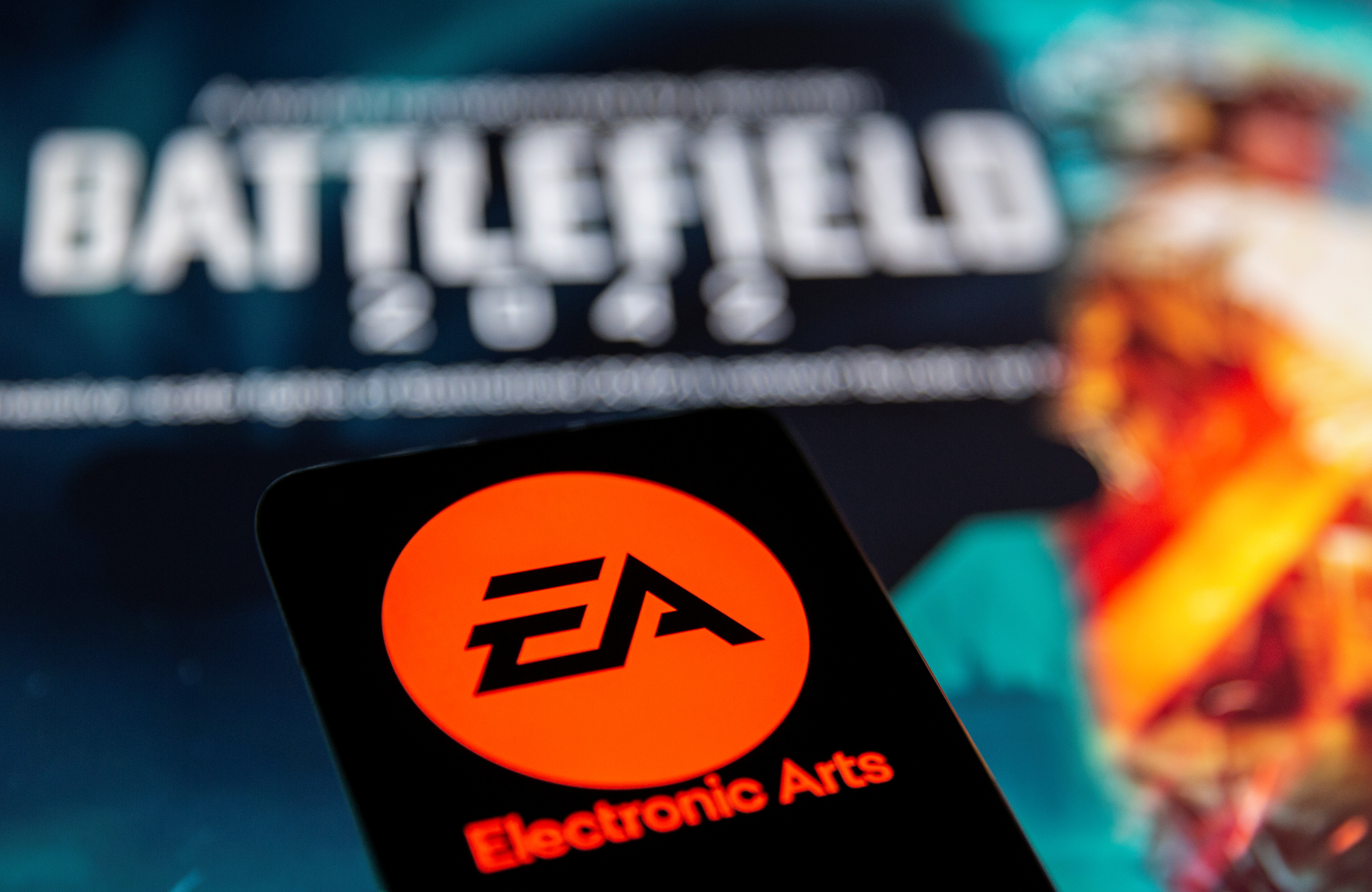 A smartphone with the Electronic Arts logo is seen in front of a displayed Battlefield 2042 logo.