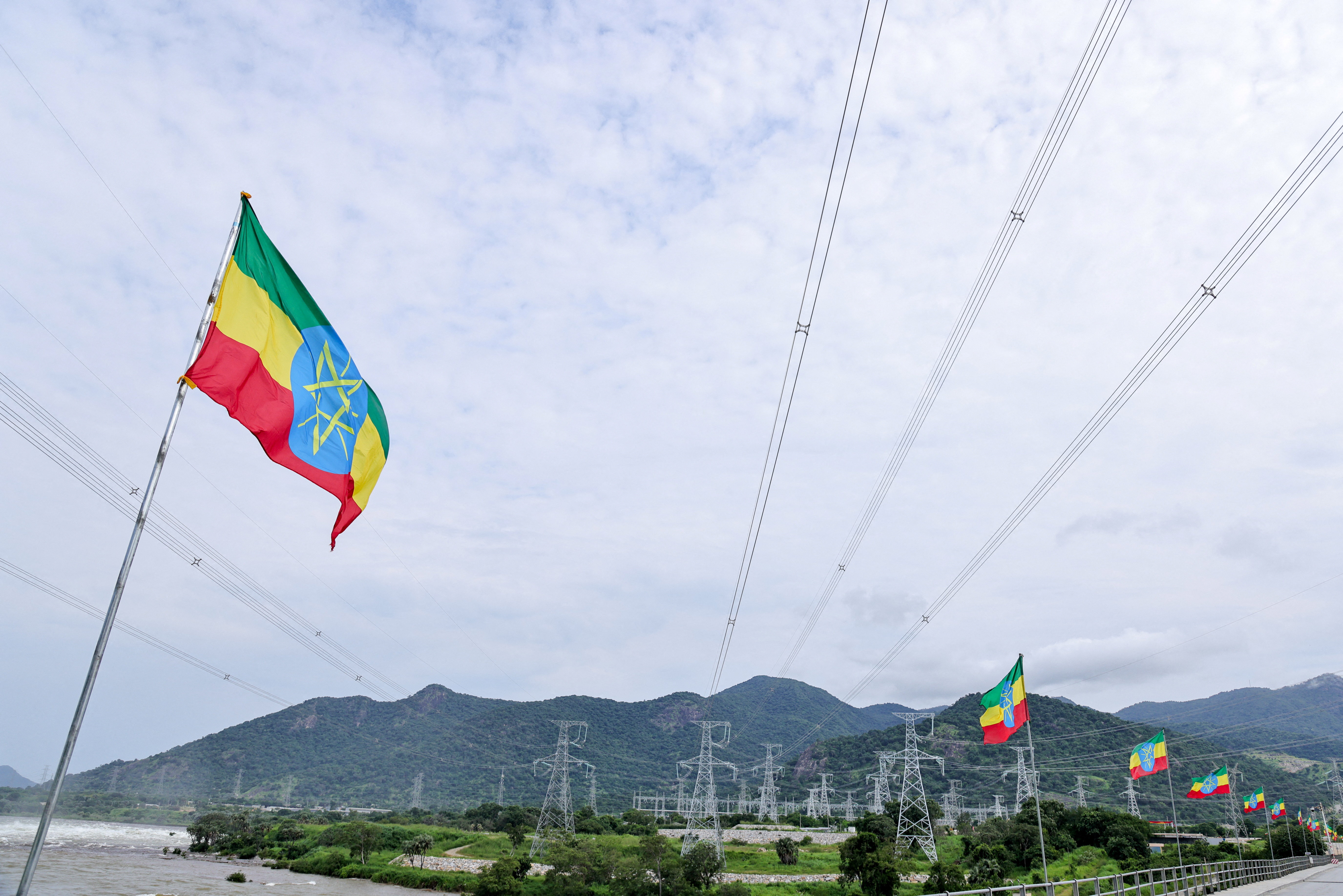 Ethiopian flags flutter in the wind next to a power station.