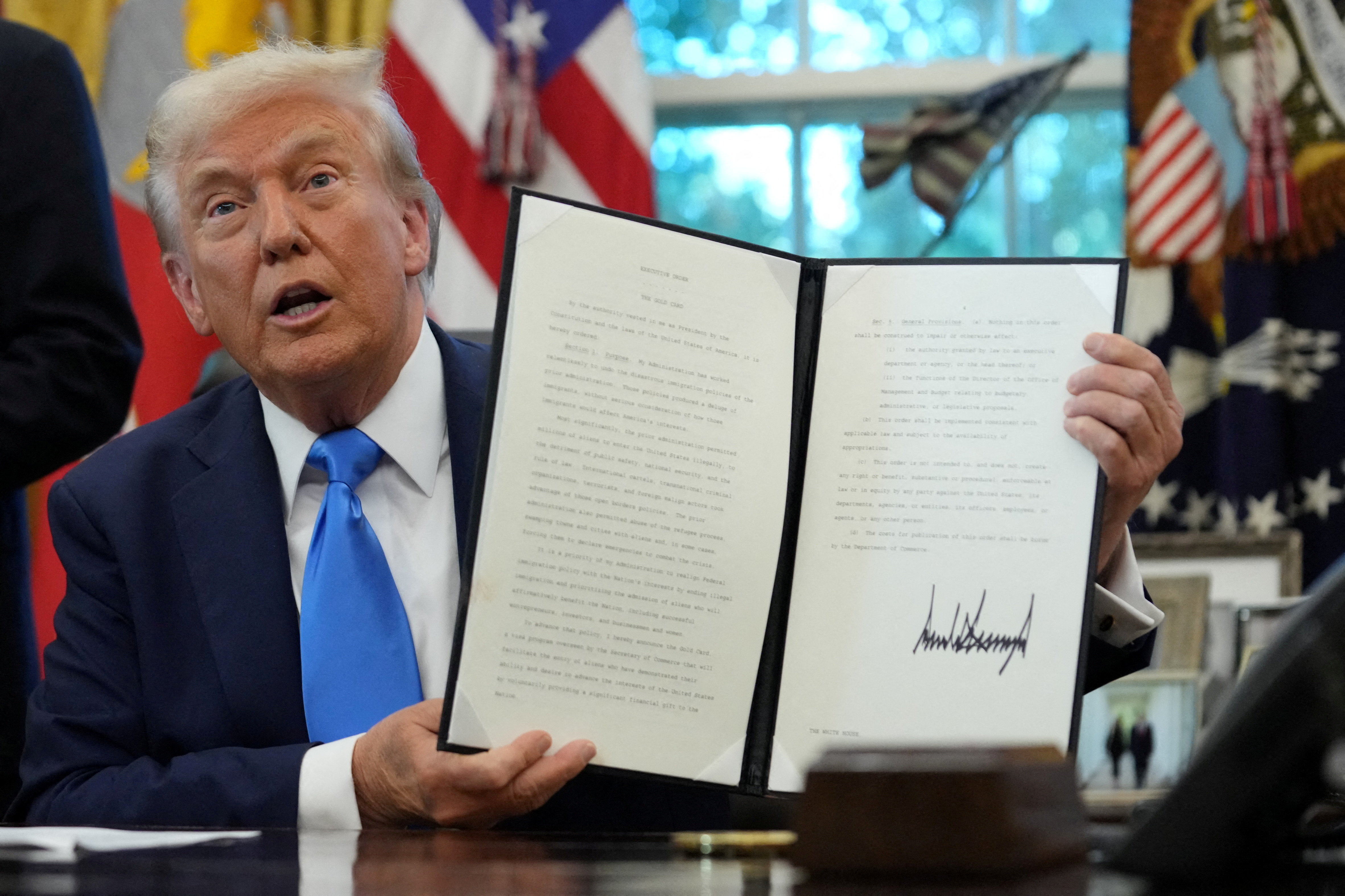 U.S. President Donald Trump displays a signed executive order on gold card visa in the Oval Office at the White House in Washington, D.C., U.S., September 19, 2025.