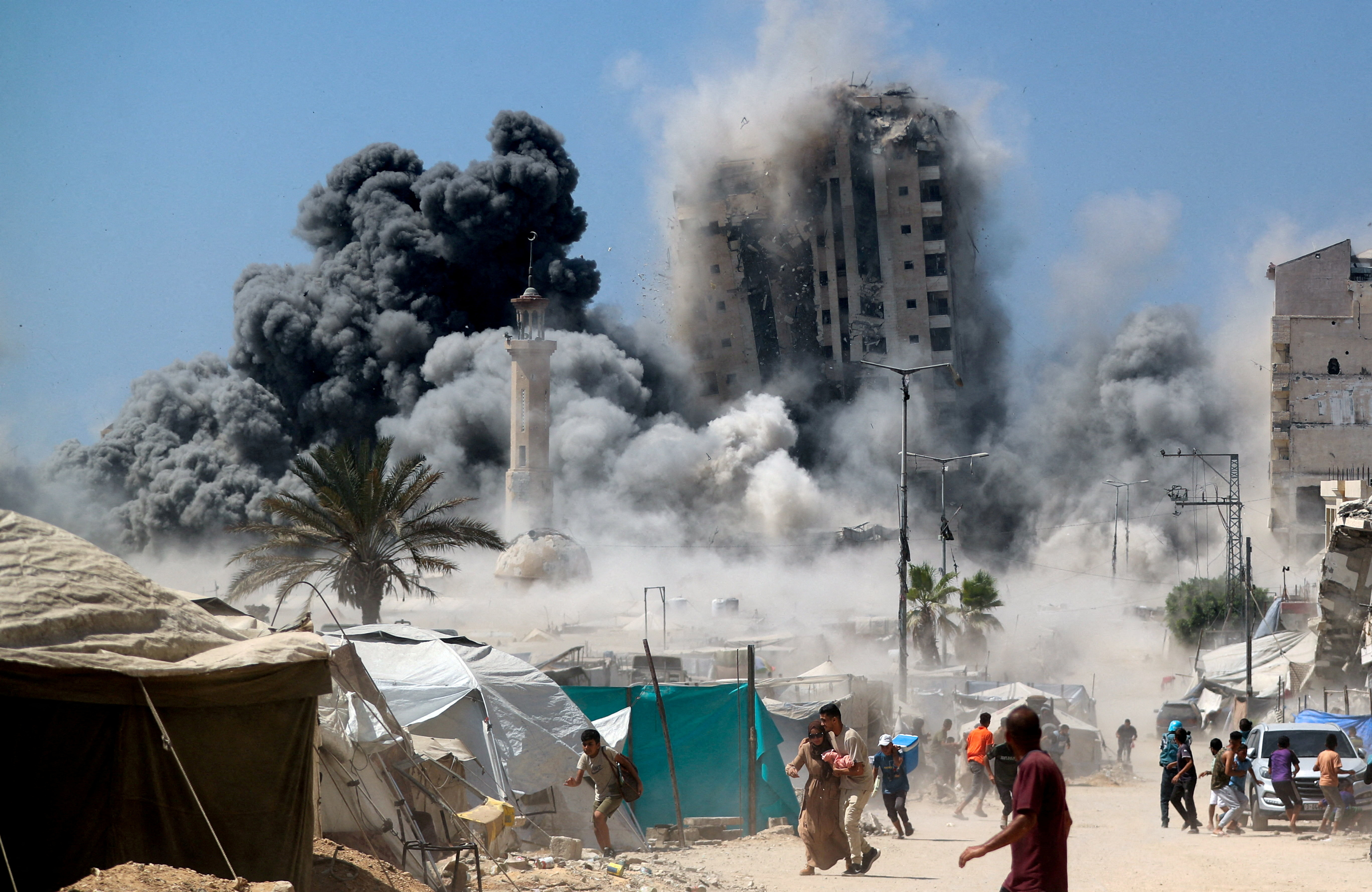 FILE PHOTO: Palestinians run as the 15-storey Mushtaha Tower collapses after being hit by an Israeli air strike, in Gaza City, September 5, 2025. REUTERS/Mahmoud Issa/File Photo