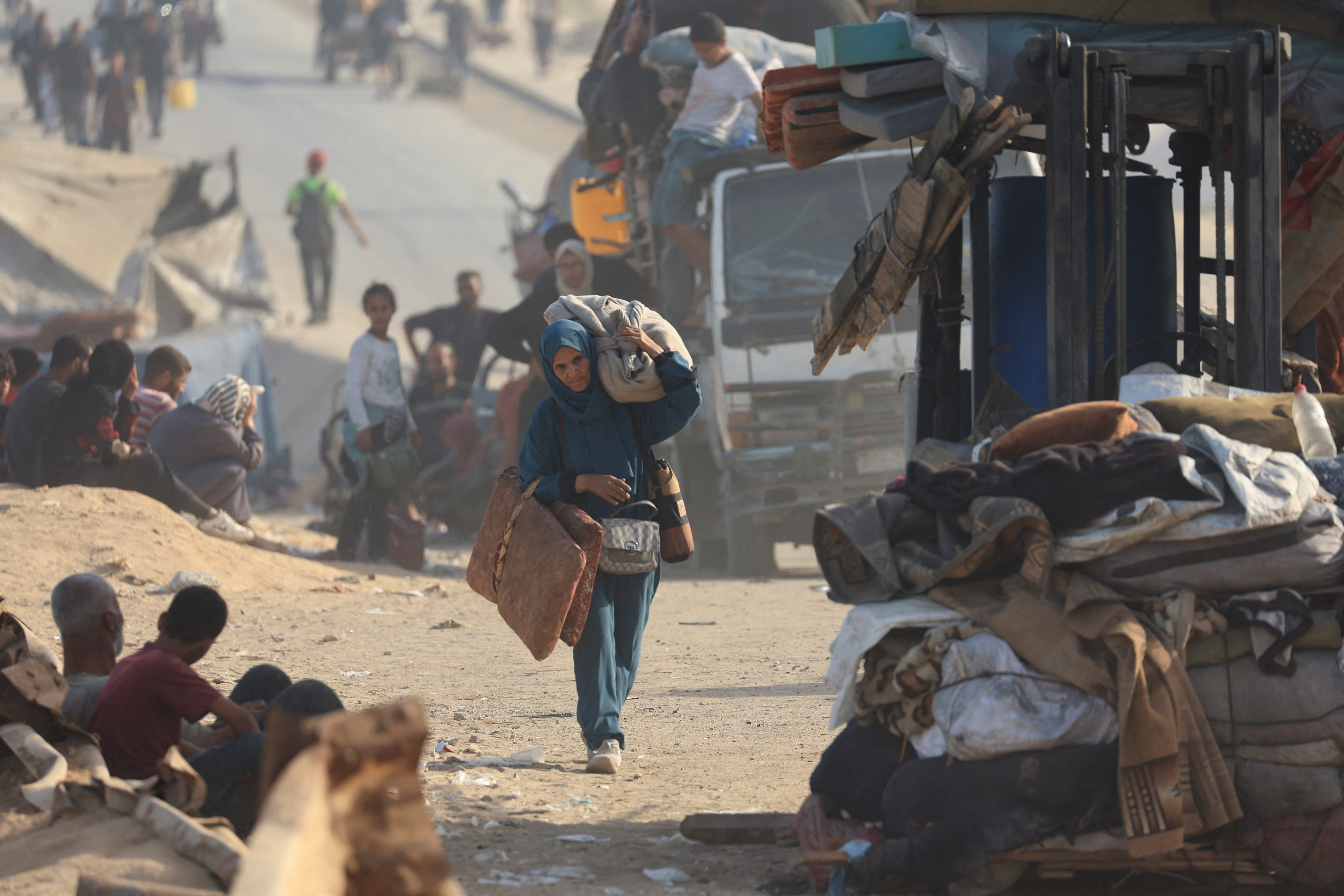 A displaced Palestinian woman, fleeing northern Gaza due to an Israeli military operation, walks with he belongings as she moves southward after Israeli forces ordered residents of Gaza City