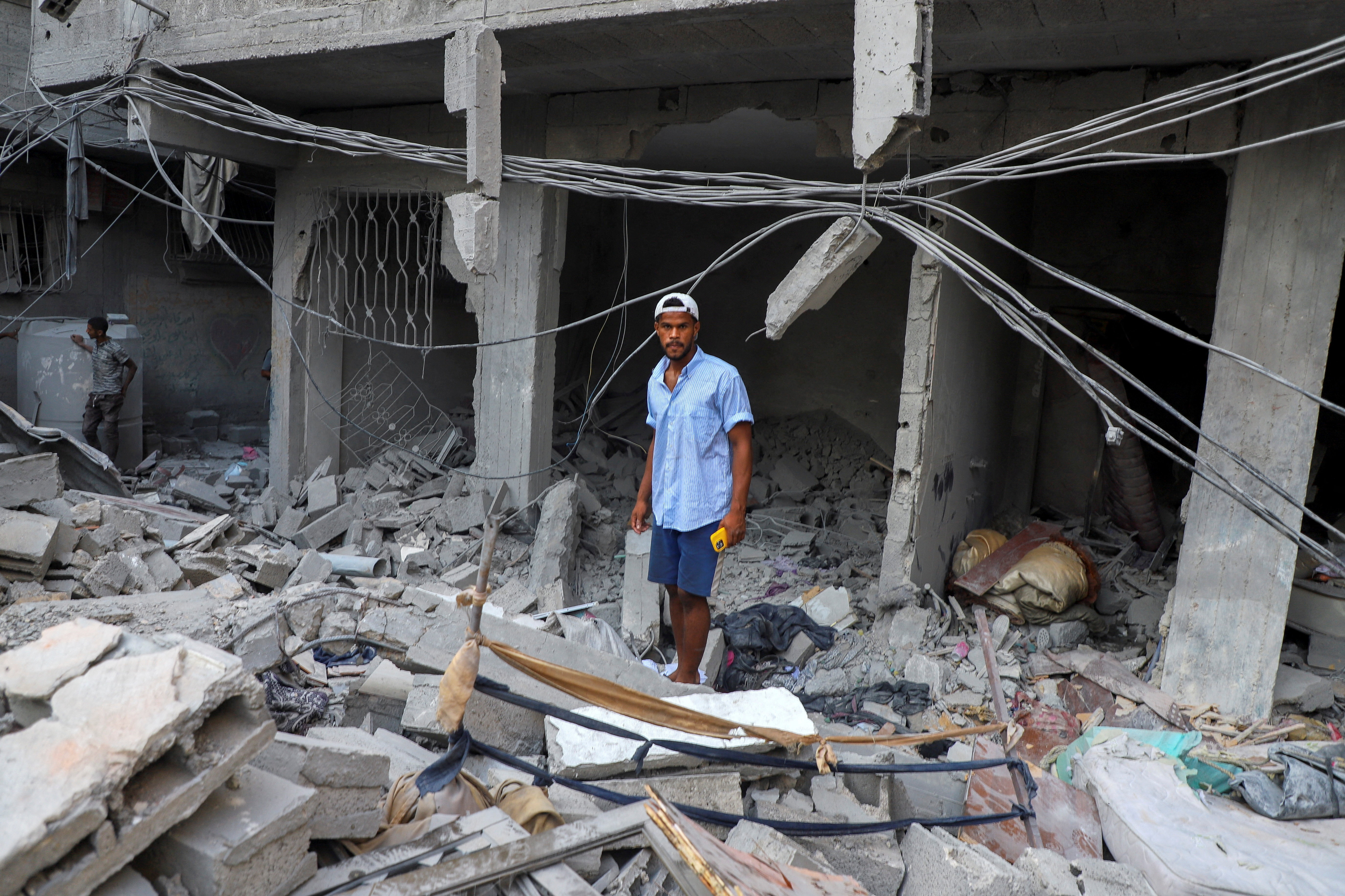 A Palestinian man stands amidst the rubble at the site of Israeli strikes on houses at Shati (Beach) refugee camp