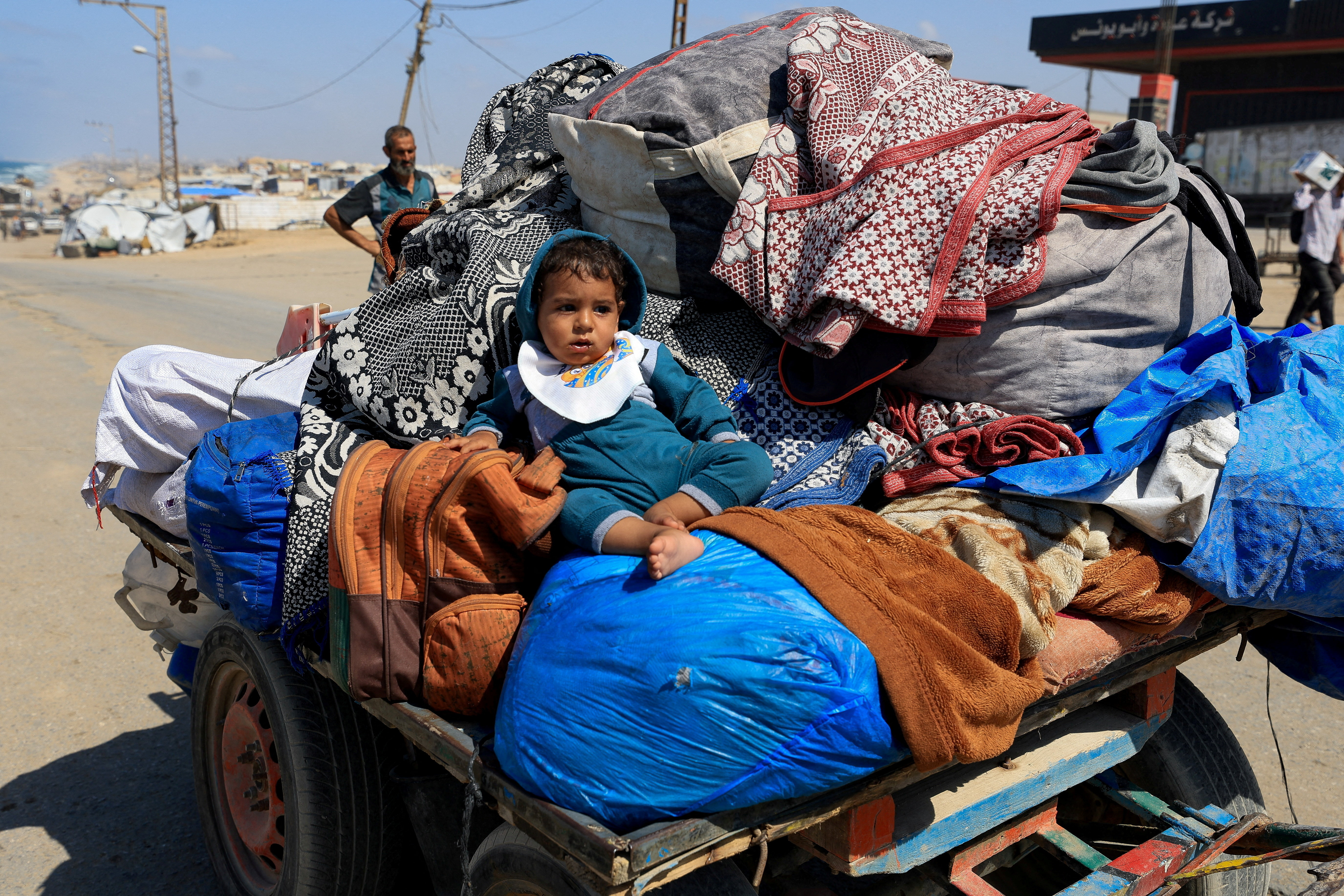 A child sits among belongings on a cart, as displaced Palestinians, fleeing northern Gaza due to an Israeli military operation, move southward