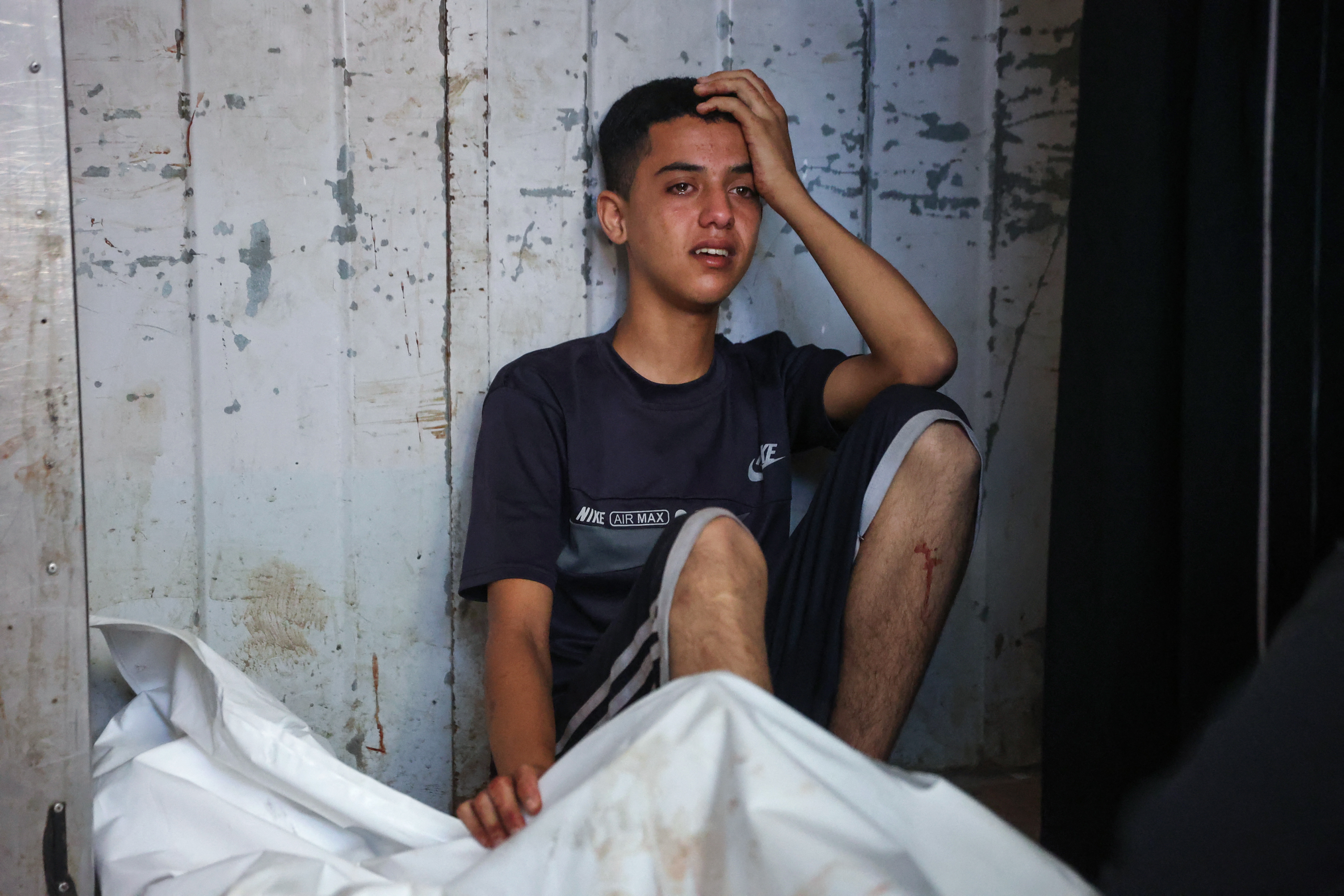 A Palestinian youth mourns by the body of a relative killed in Israeli strikes on Gaza City at dawn at Al-Shifa hospital