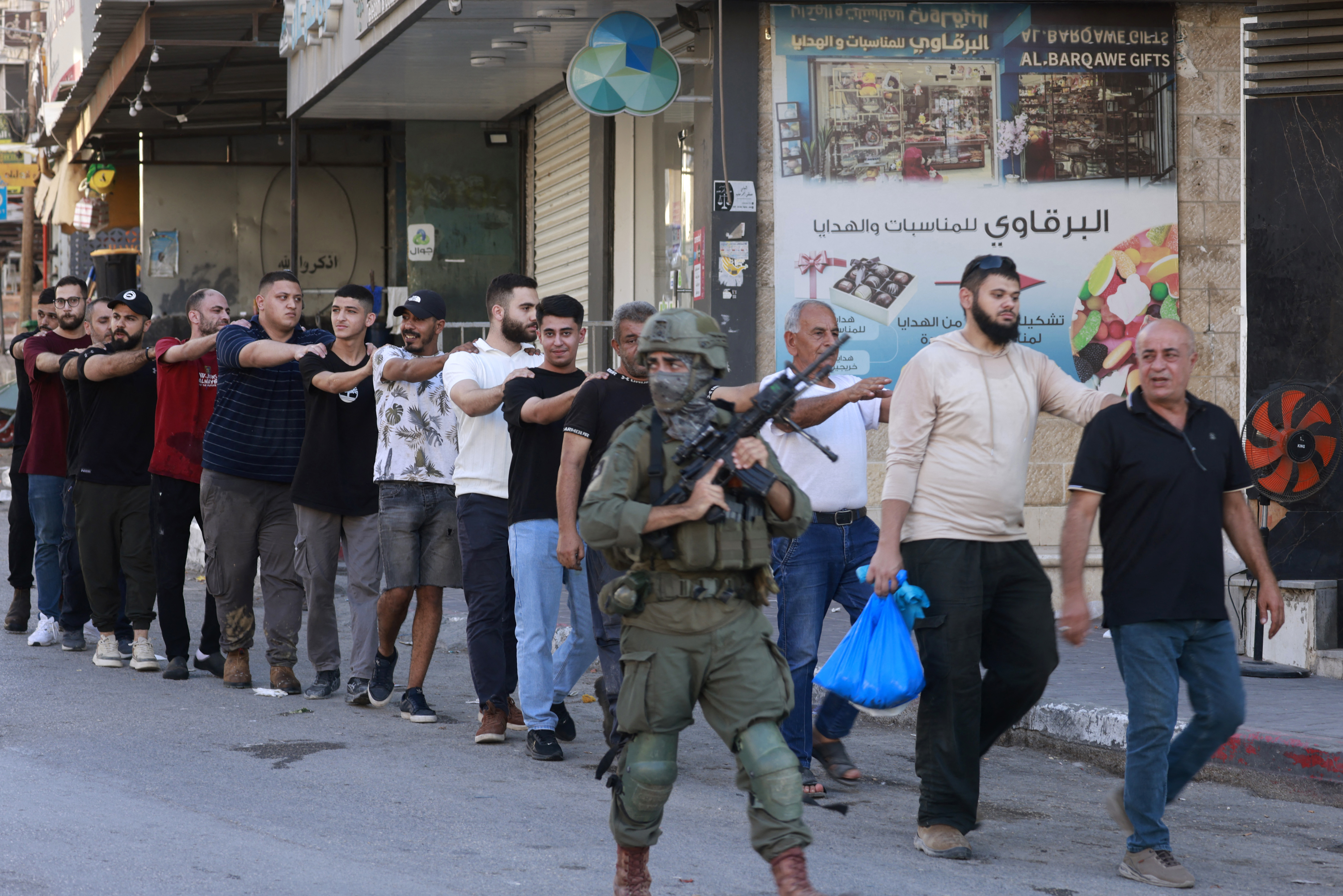 Israeli soldiers detain Palestinians near a checkpoint west of Tulkarem in the occupied West Bank [Jaafar Ashtiyeh/AFP]