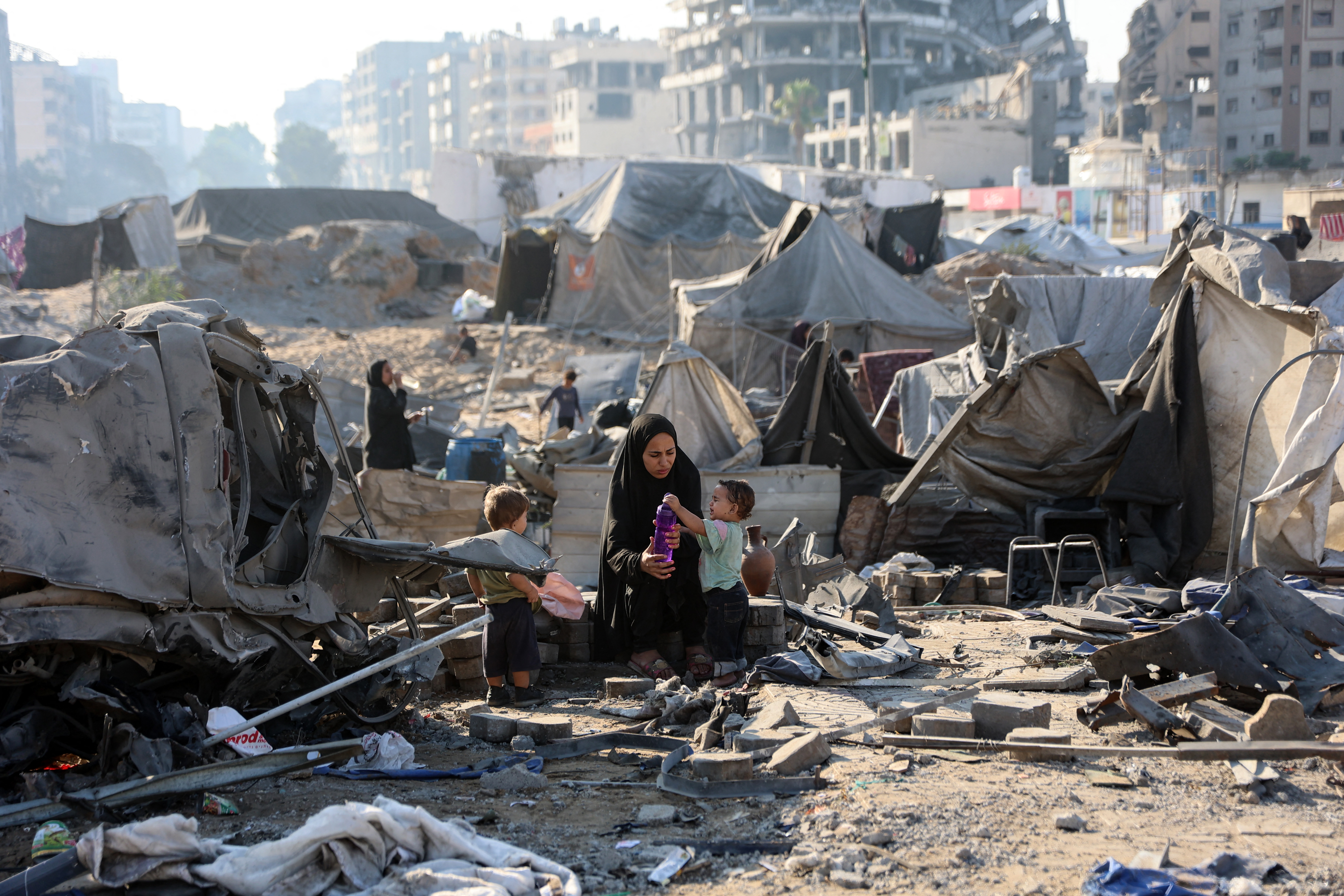 A displaced Palestinian woman sits with children after Israeli strike