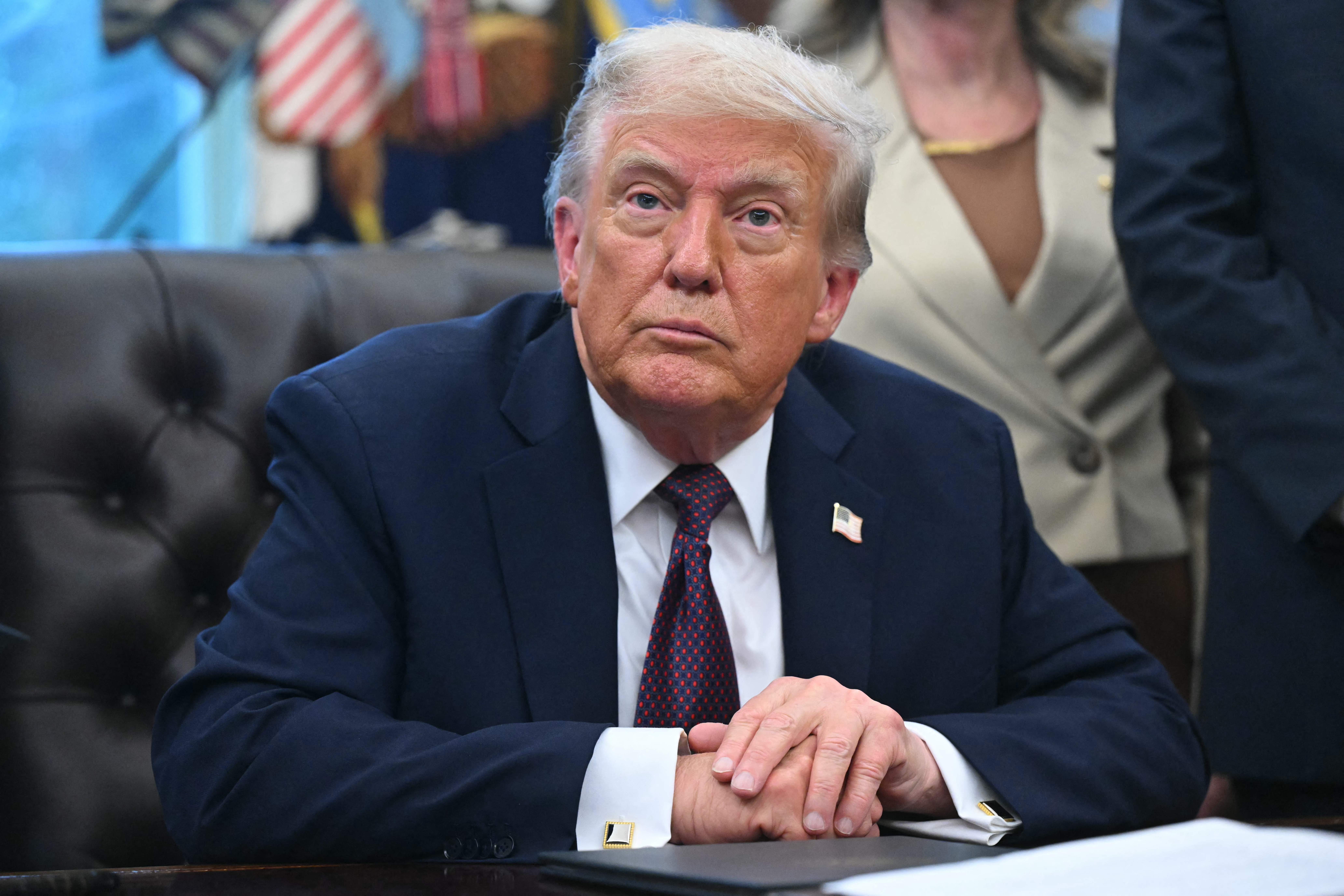 US President Donald Trump looks on.