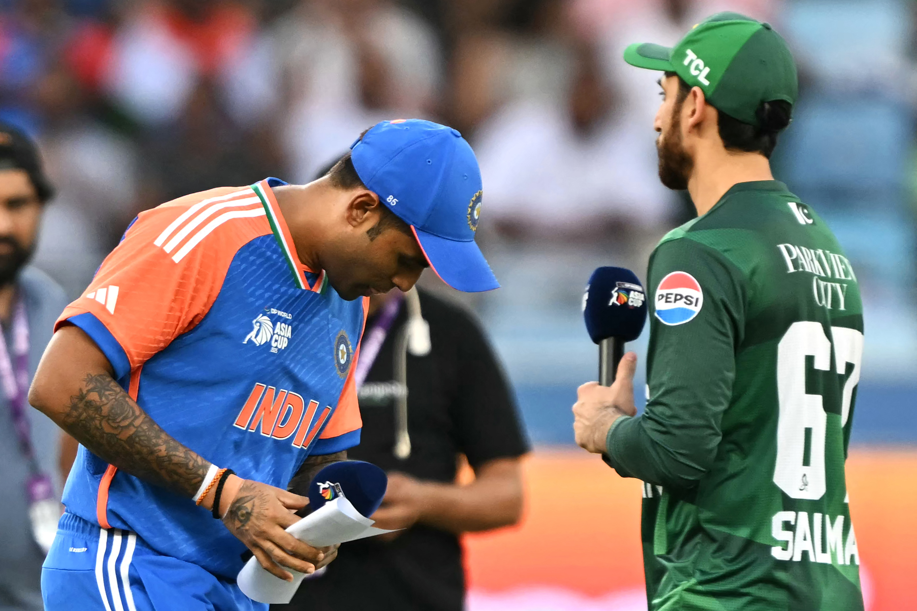 India's captain Suryakumar Yadav (L) walks after the toss as his Pakistan's counterpart Salman Agha watches before the start of the Asia Cup 2025 Super Four Twenty20 international cricket match between India and Pakistan at the Dubai International Stadium in Dubai on September 21, 2025. (Photo by Sajjad HUSSAIN / AFP)