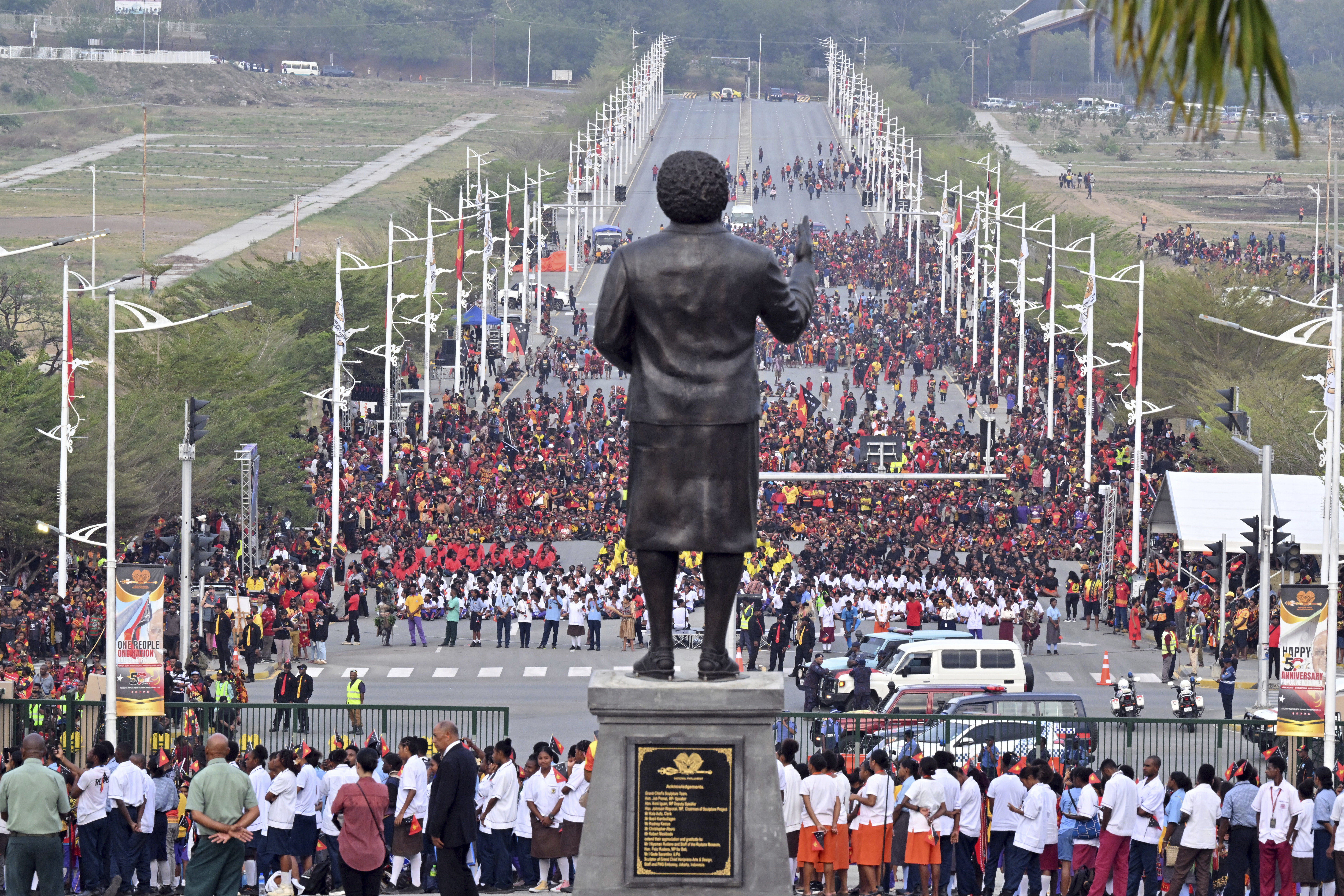 Papua New Guineans stand in front of a statue of Papua New Guinea's first Prime Minister Michael Somare