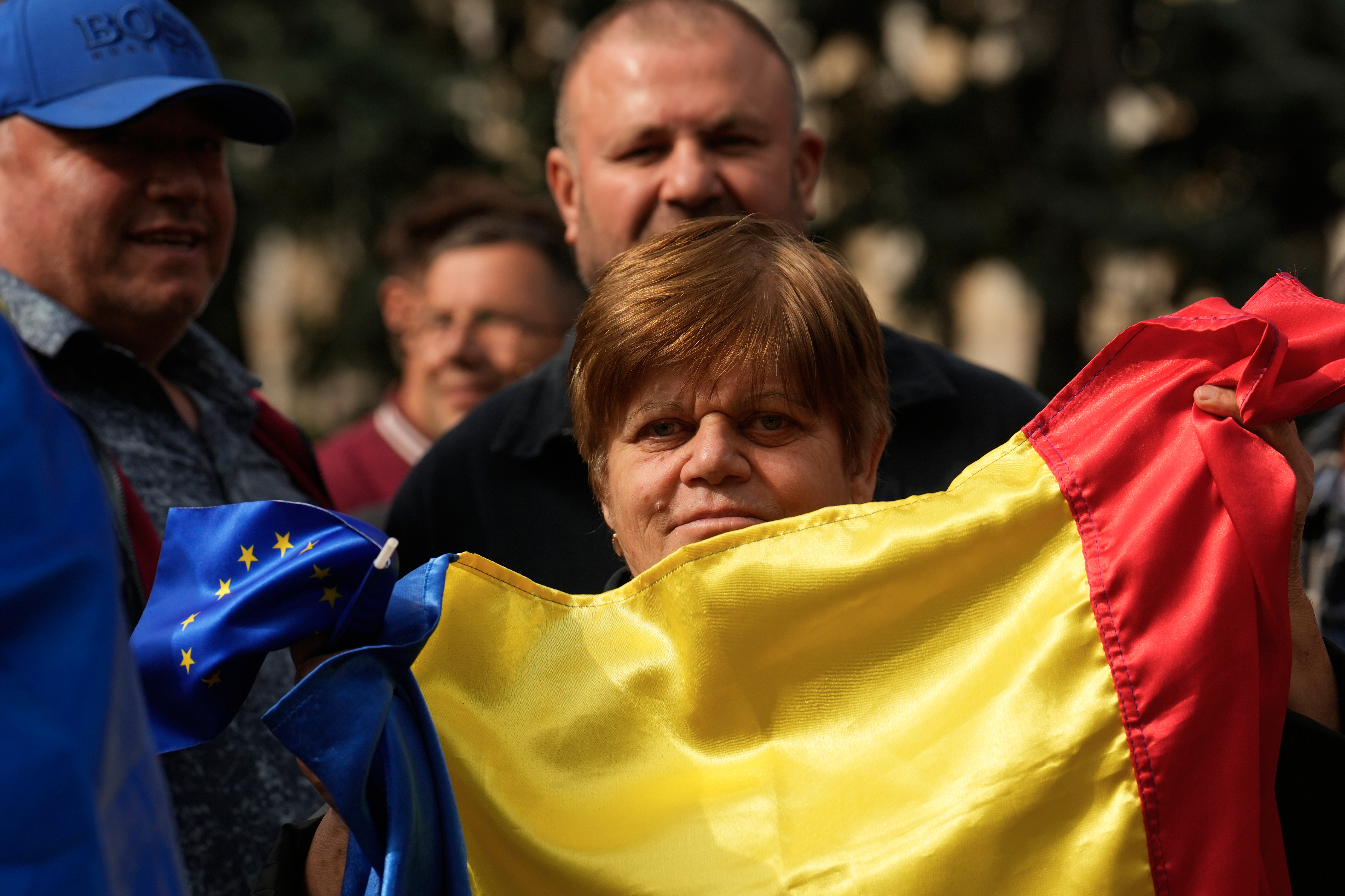 a WOMAN hols a Moldovan flag up