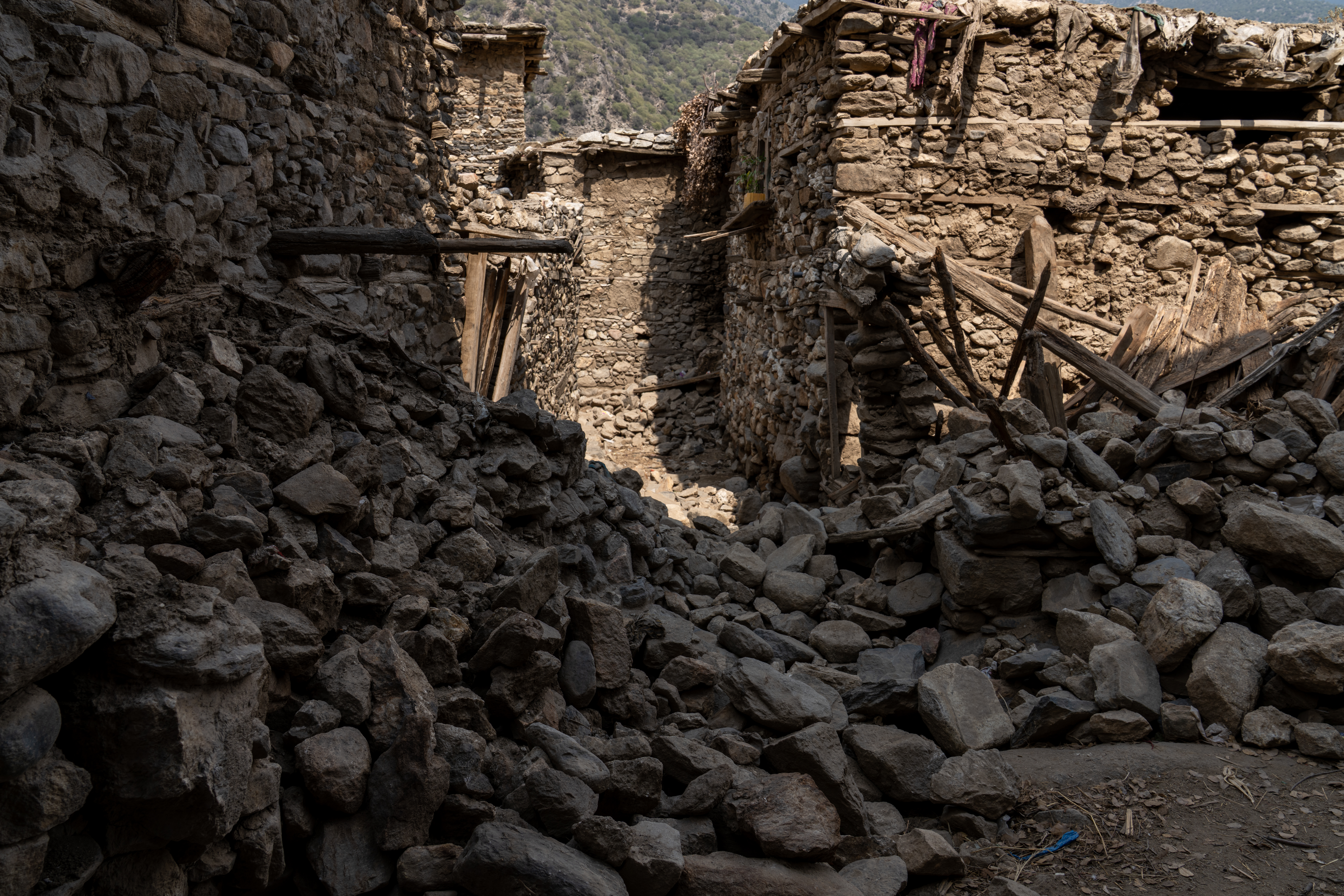 Piles of stones left behind after walls collapsed during the earthquake in Andarlachak village.