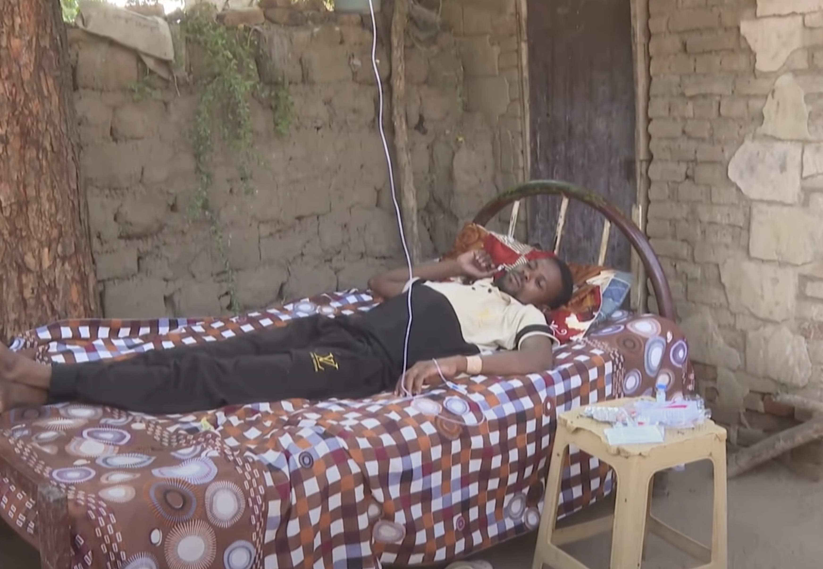 A man lies down on a bed under a tree 