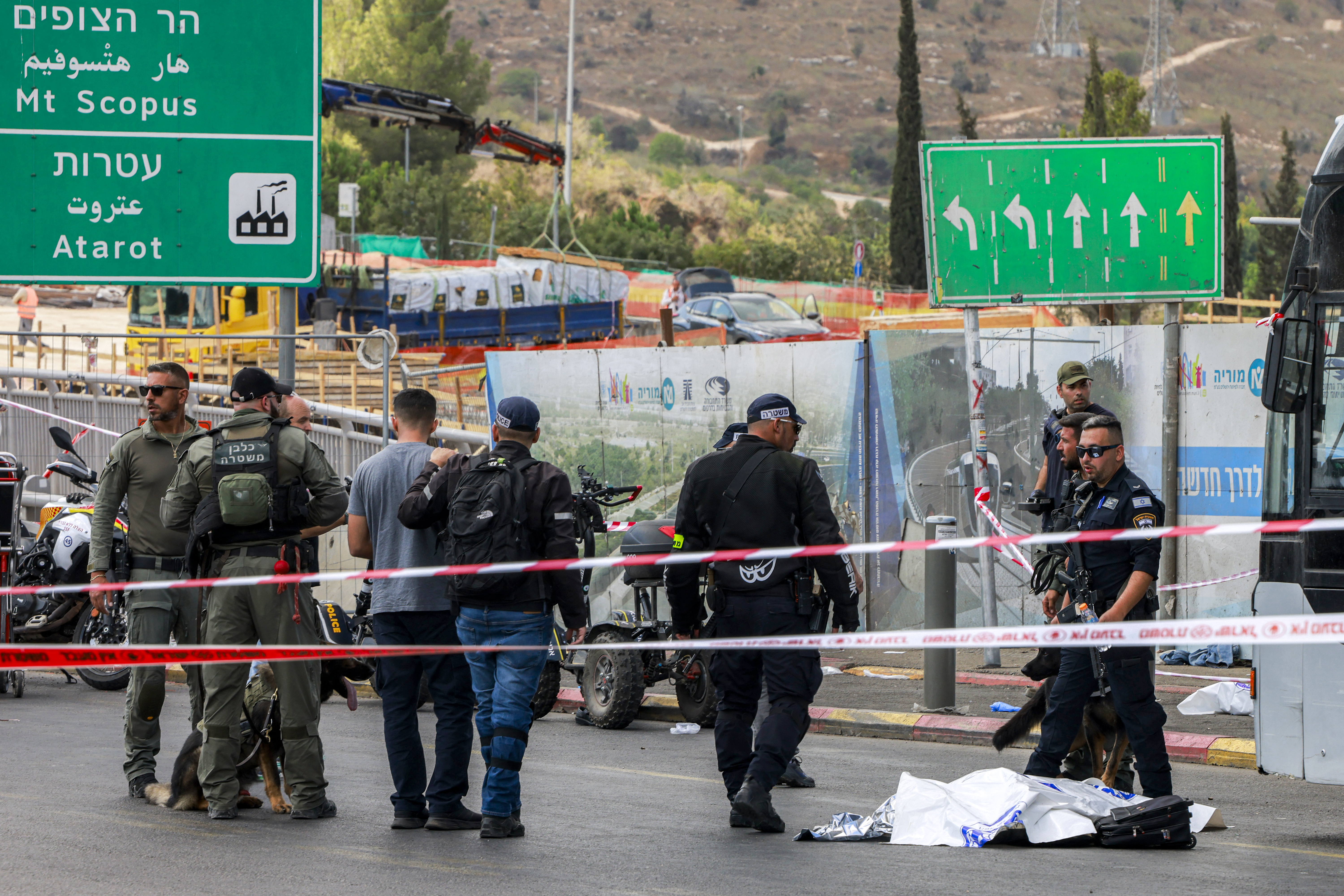 EDITORS NOTE: Graphic content / TOPSHOT - Israeli security forces gather by a body next to a bus at the Ramot road junction in Israeli-annexed east Jerusalem on September 8, 2025.