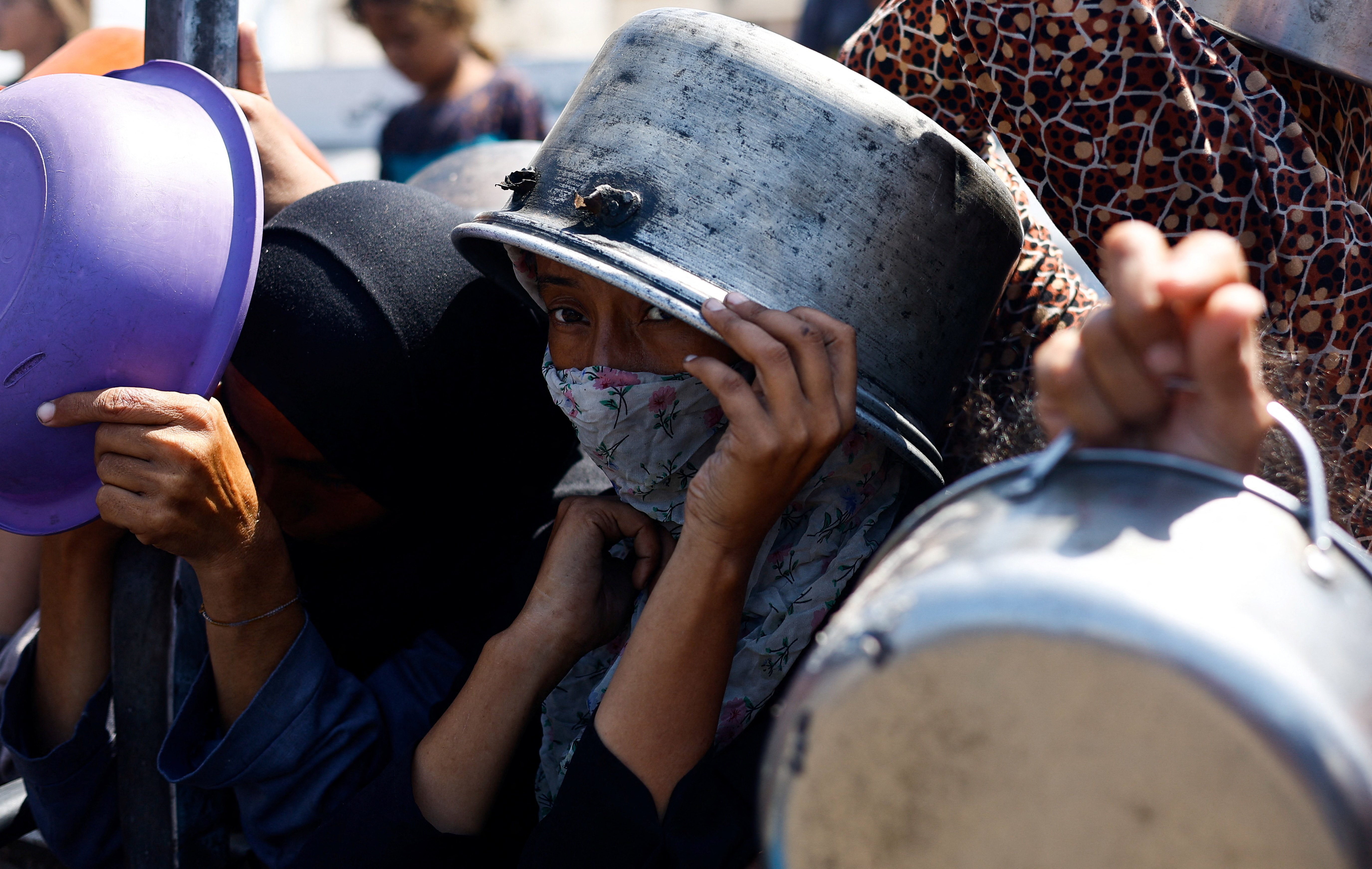 Palestinians wait to receive food from a charity kitchen in Gaza City