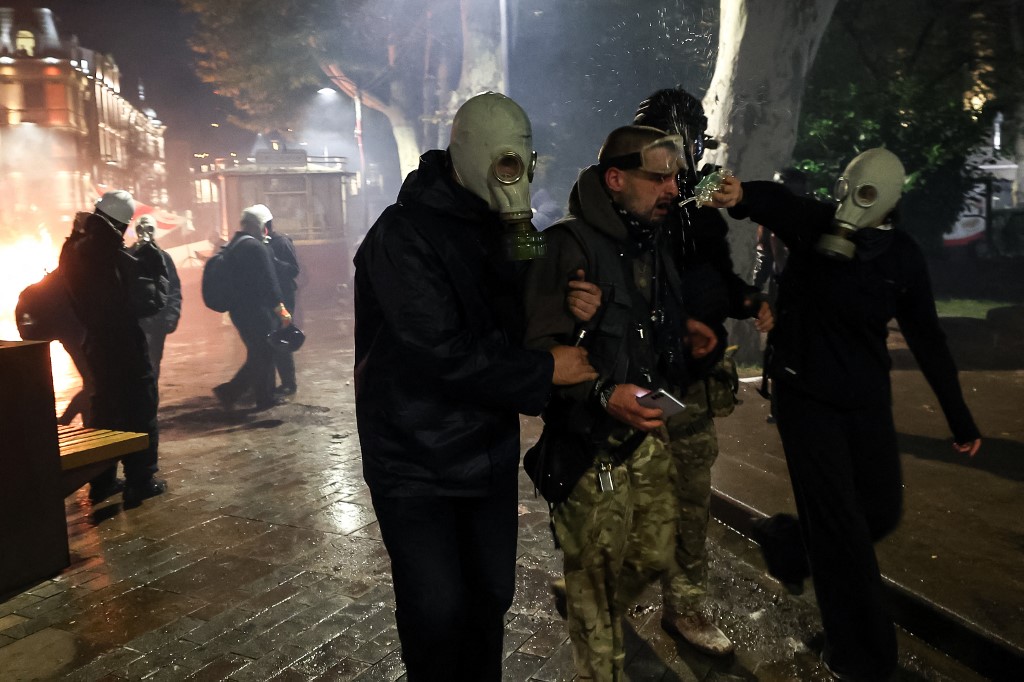 A protester receives help after being hit by tear gas during clashes with riot police during an opposition rally on the day of local elections in central Tbilisi on October 4, 2025. [Giorgi Arjevanidze/AFP]