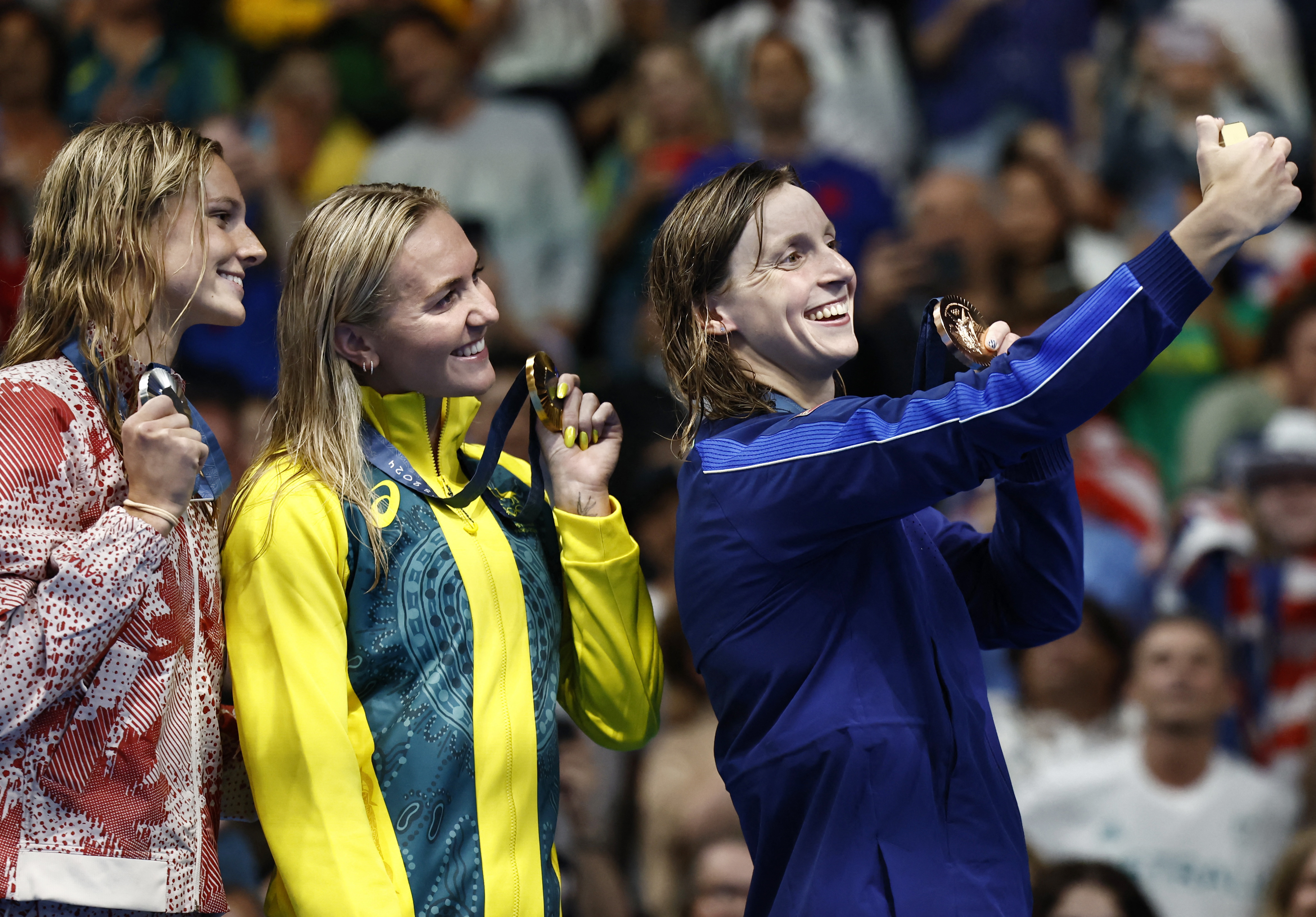 Ariarne Titmus, Summer McIntosh and Katie Ledecky react.