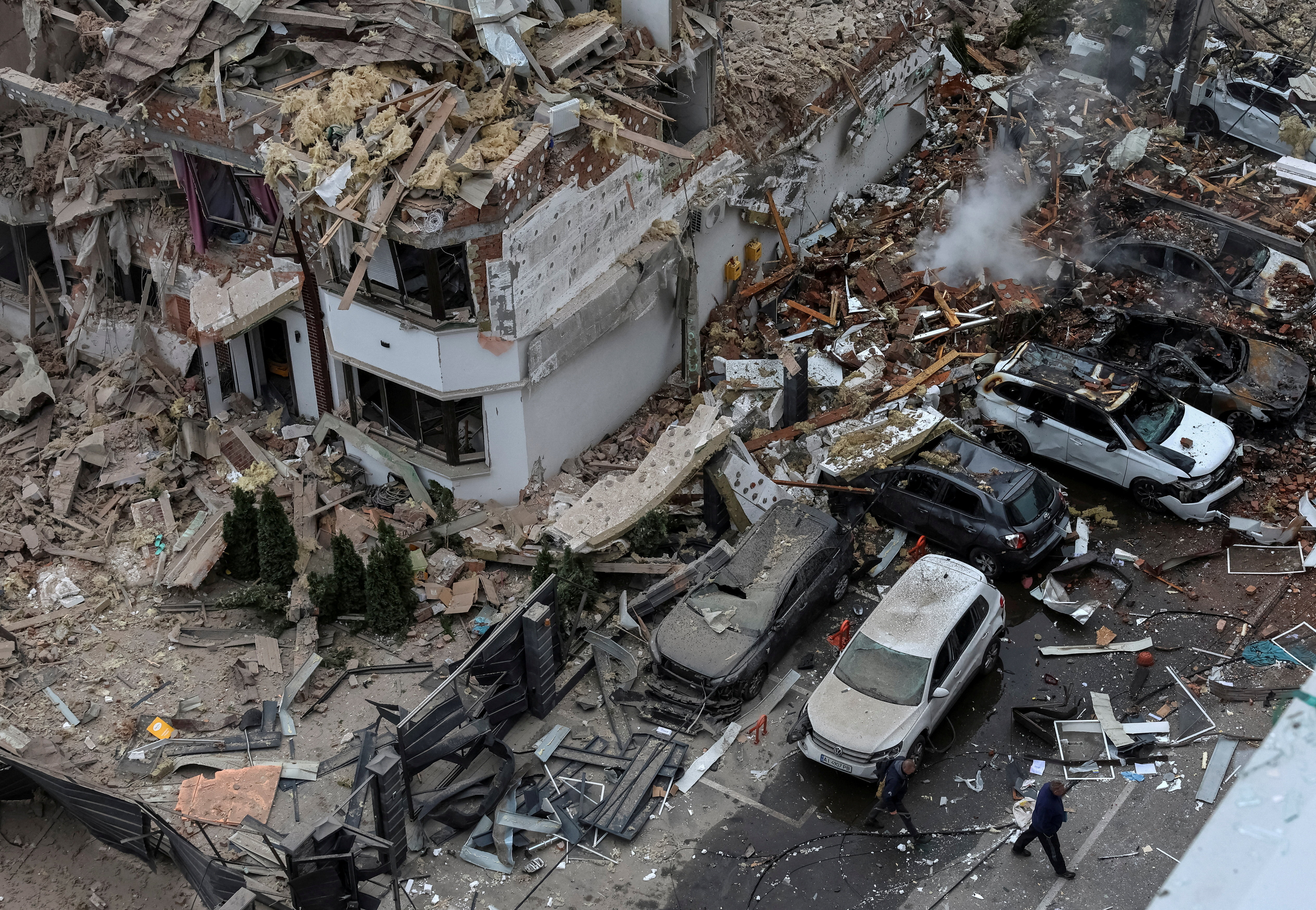 People walk next to a damaged building and vehicles in a residential neighbourhood hit during a Russian drone and missile strike, amid Russia's attack on Ukraine, on the outskirts of Kyiv, Ukraine, September 28, 2025. REUTERS/Anatolii Stepanov TPX IMAGES OF THE DAY
