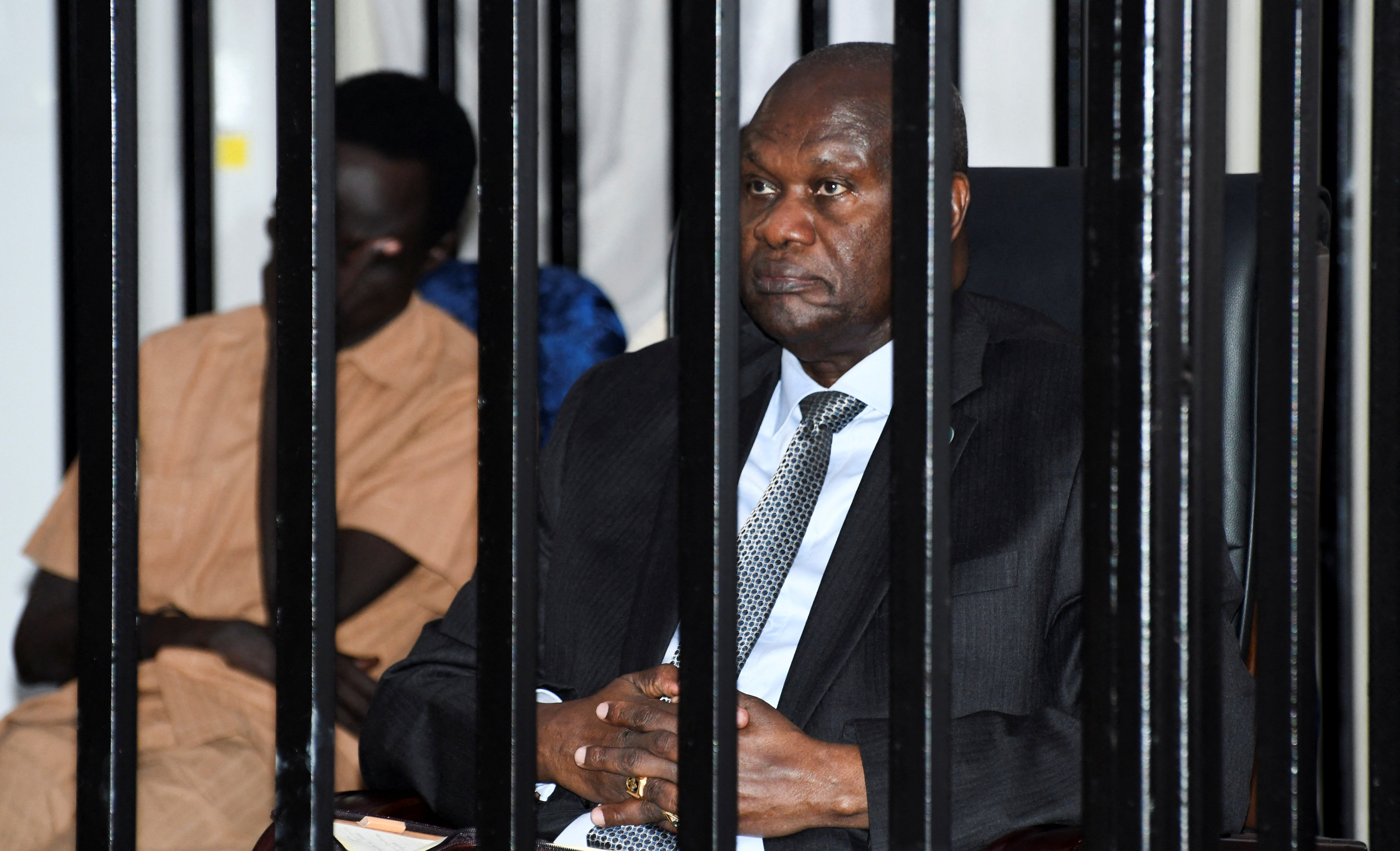 South Sudan’s suspended First Vice President Riek Machar sits inside a steel cage dock during his trial.